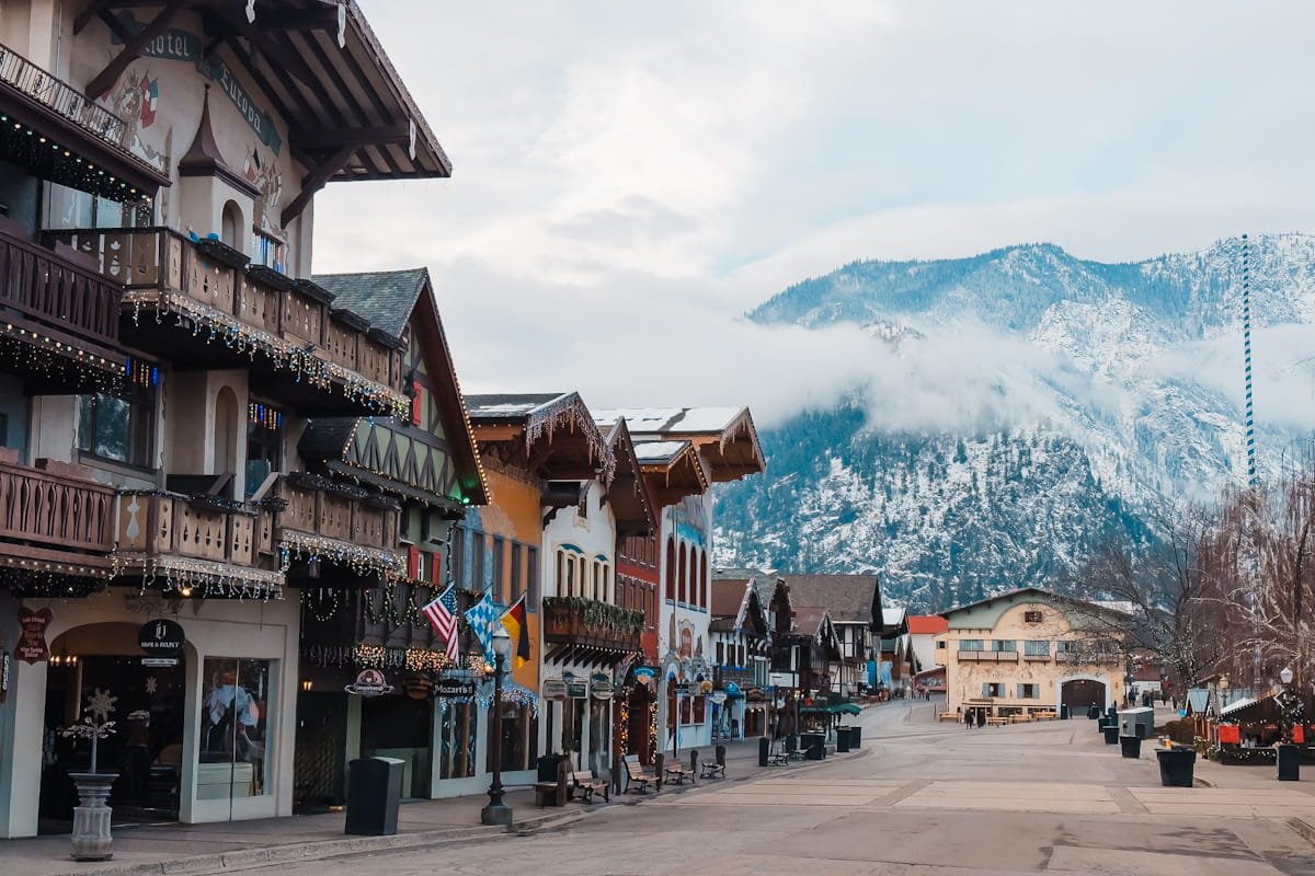 bavarian themed buildings on the main street in downtown leavenworth, washington with mountains in the background