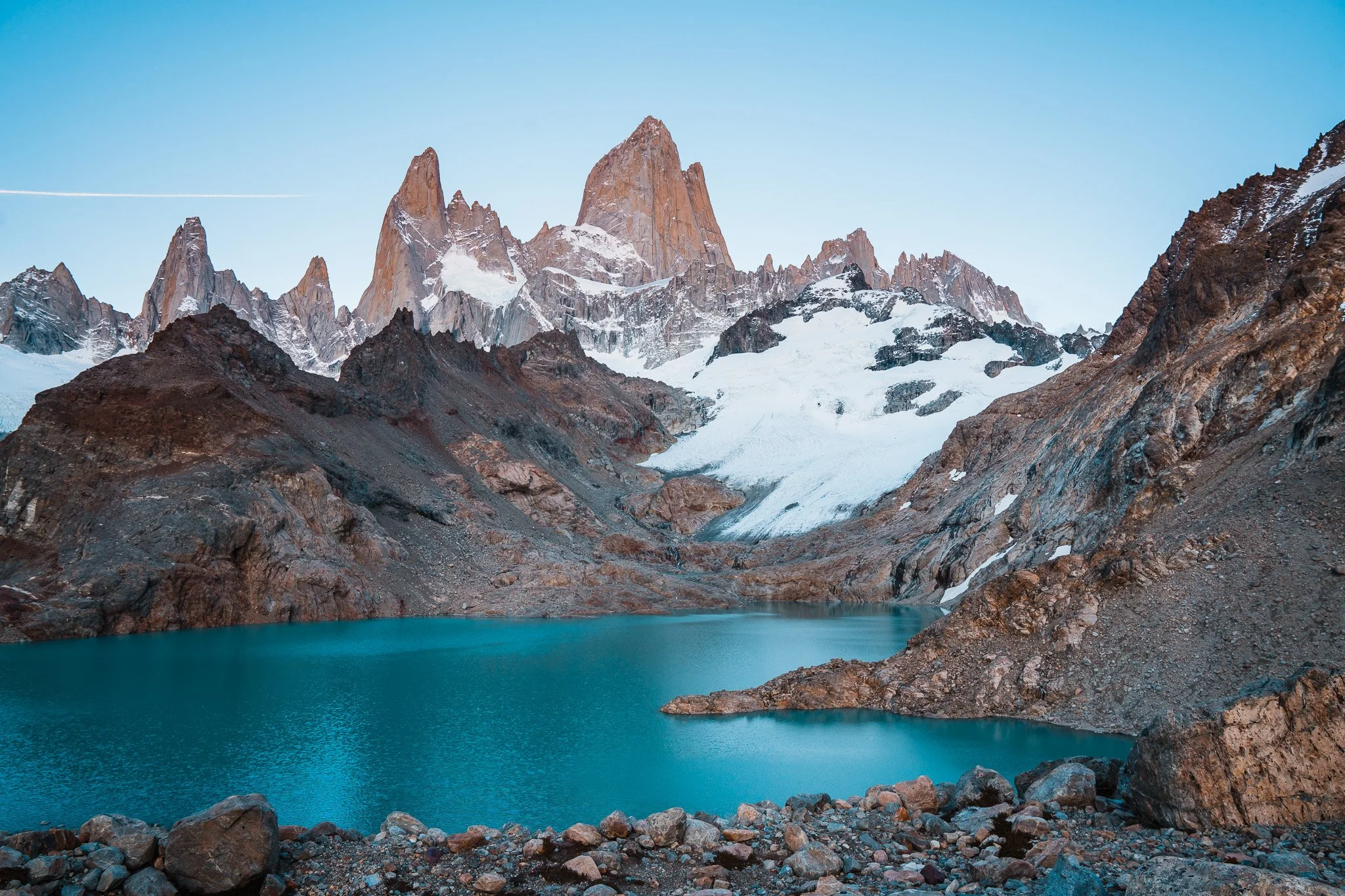 a bright turquoise blue lake with glaciers and dramatic rocky mountains of the Fitz Roy range in El Chalten, Patagonia