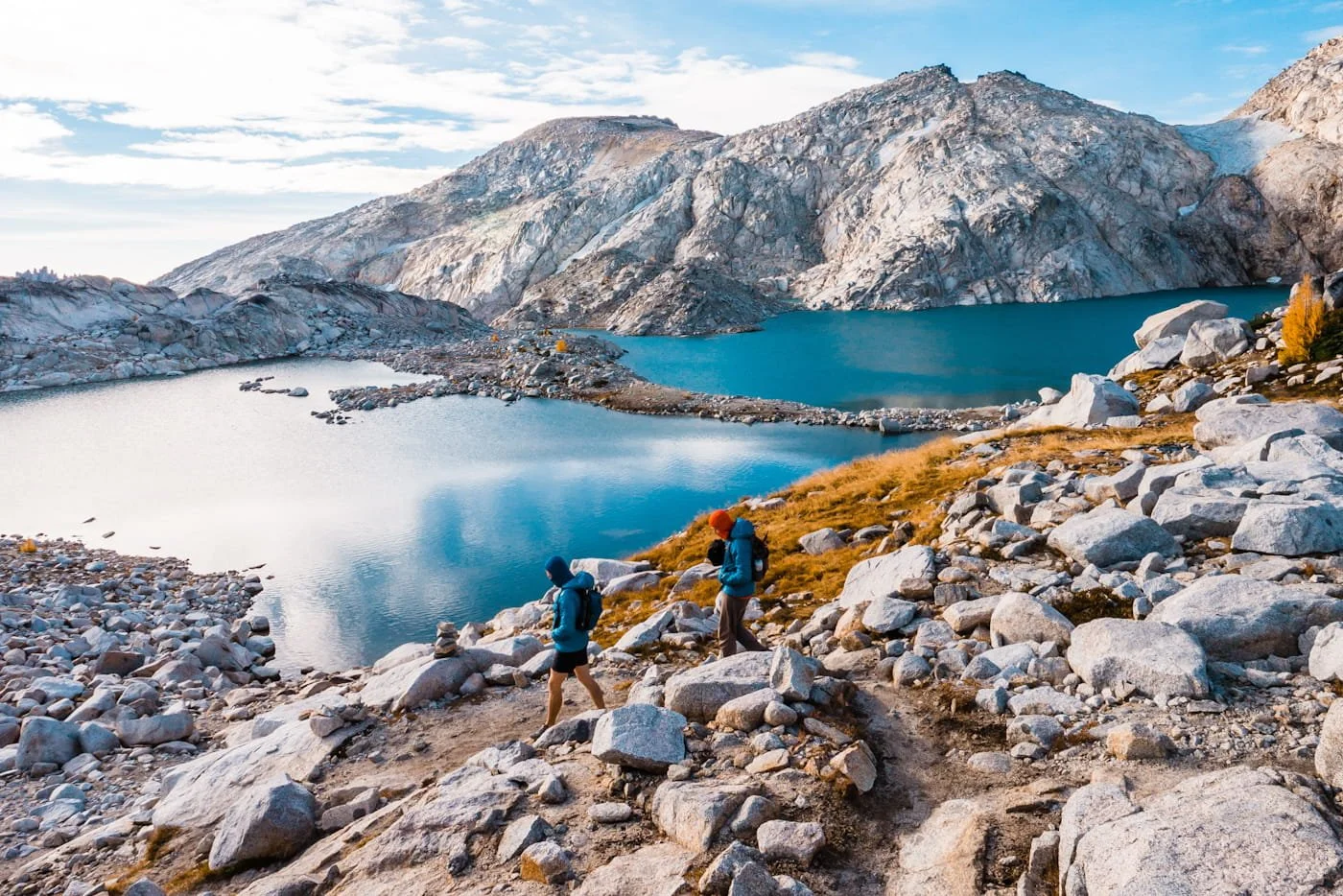 two day hikers heading down the trail in the upper core enchantments with two blue lakes and rocky peaks in the background