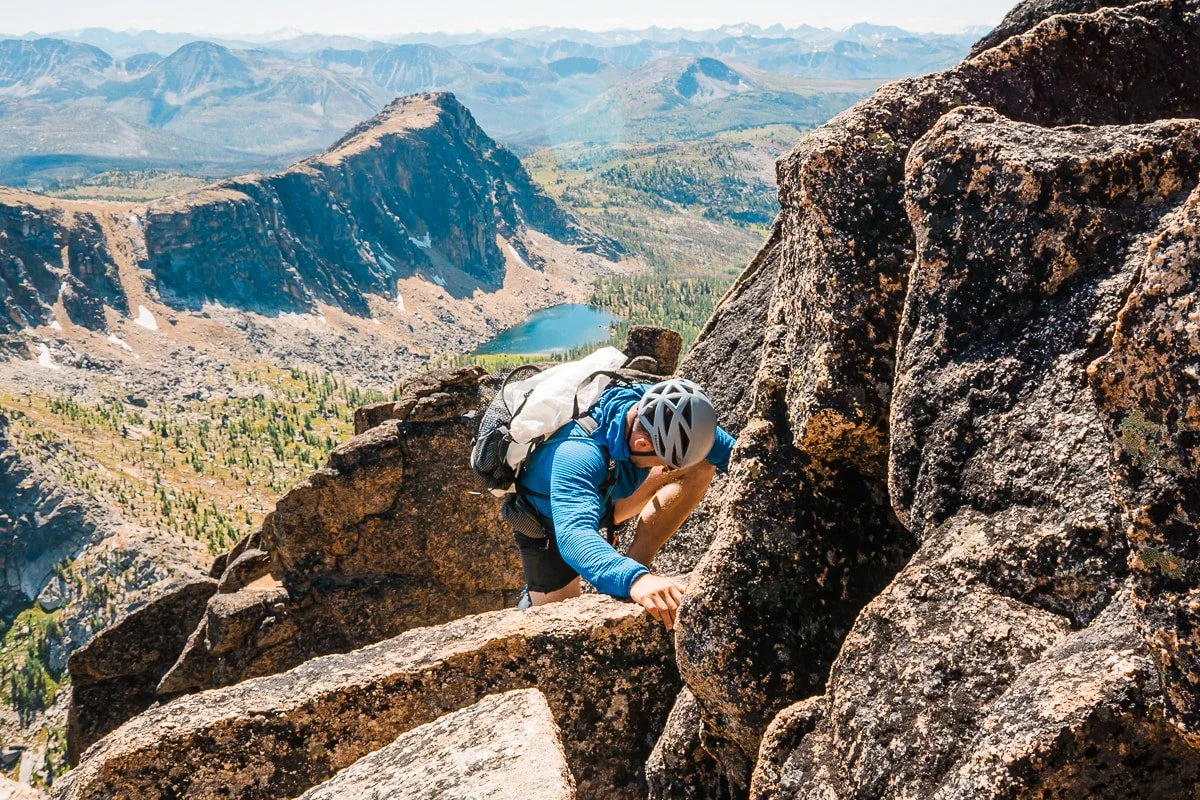 a man climbing up rocks on the scramble up cathedral peak in the pasayten wilderness