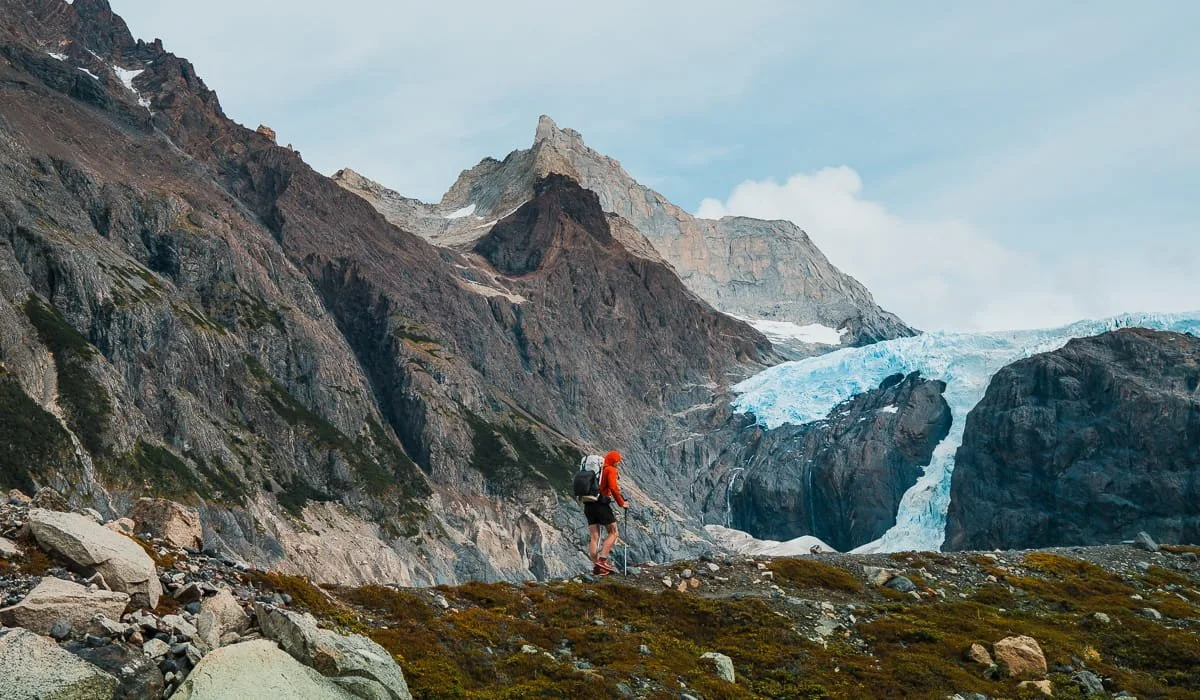 A man backpacking in a bright red shirt and white hyperlite backpack on the o-circuit in patagonia
