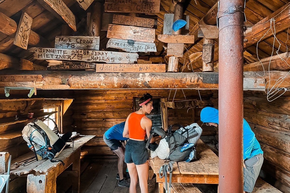 backpackers inside an old cabin filled with wooden signs