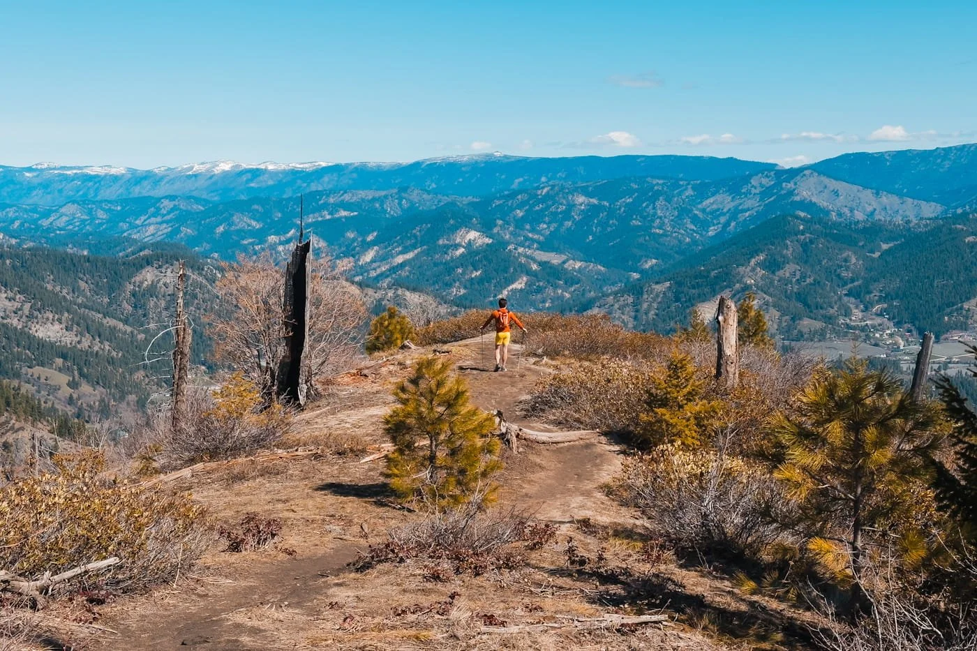 A hiker walking on a trail to a view point overlooking hills and the town of leavenworth