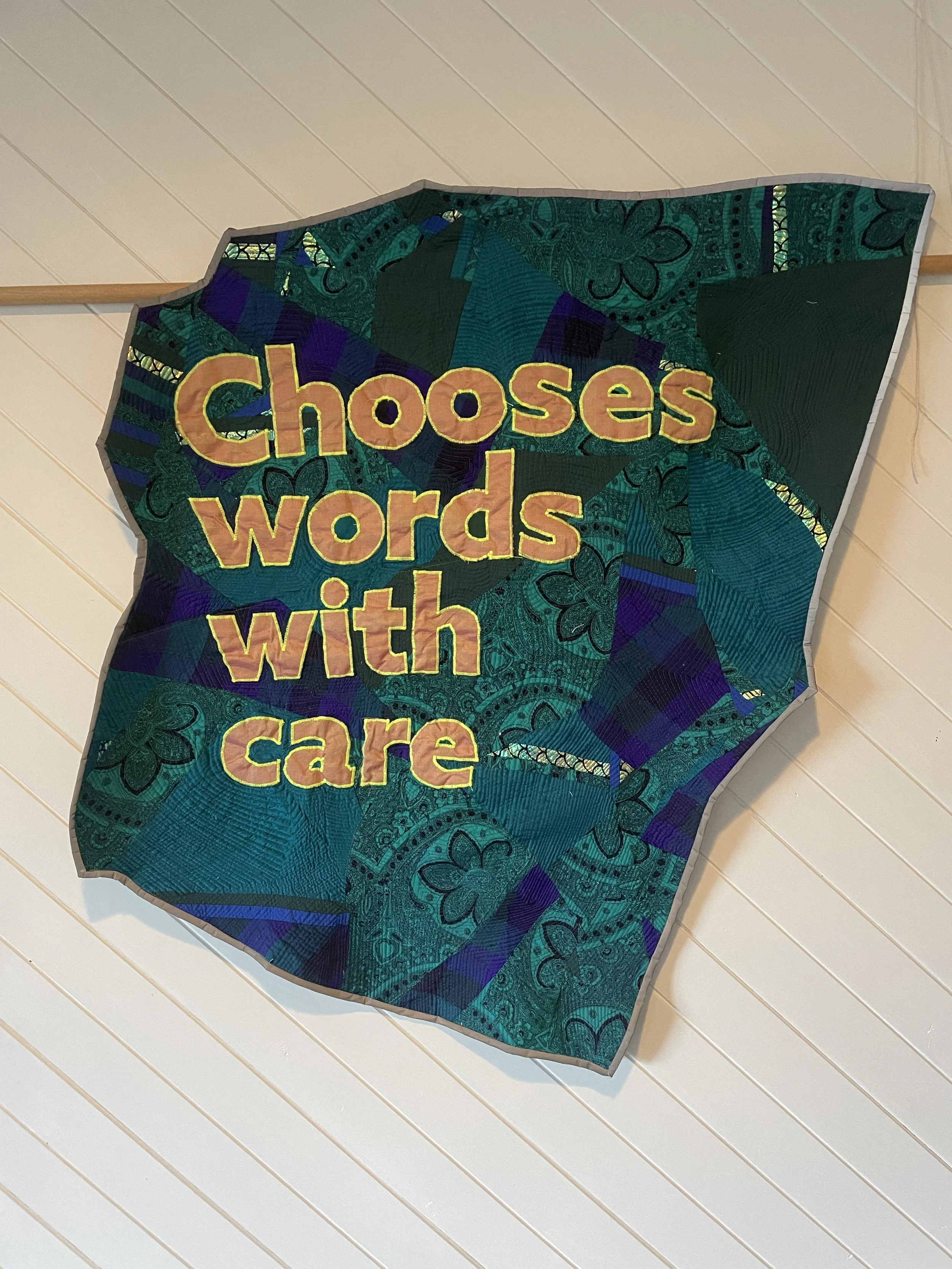 Banner quilt with appliqué lettering reading Chooses words with care