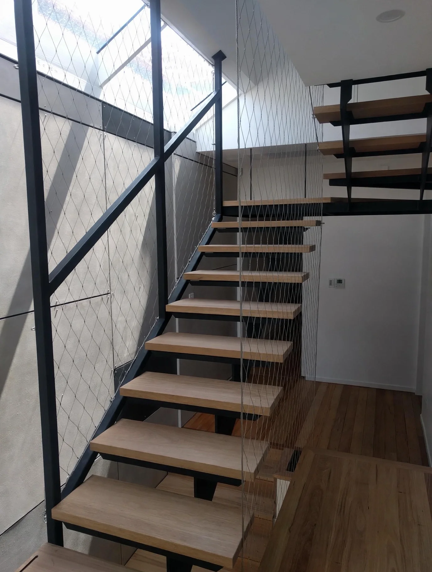 Staircase detail with dramatic natural light and shadow across board-formed concrete wall, Marrickville bungalow