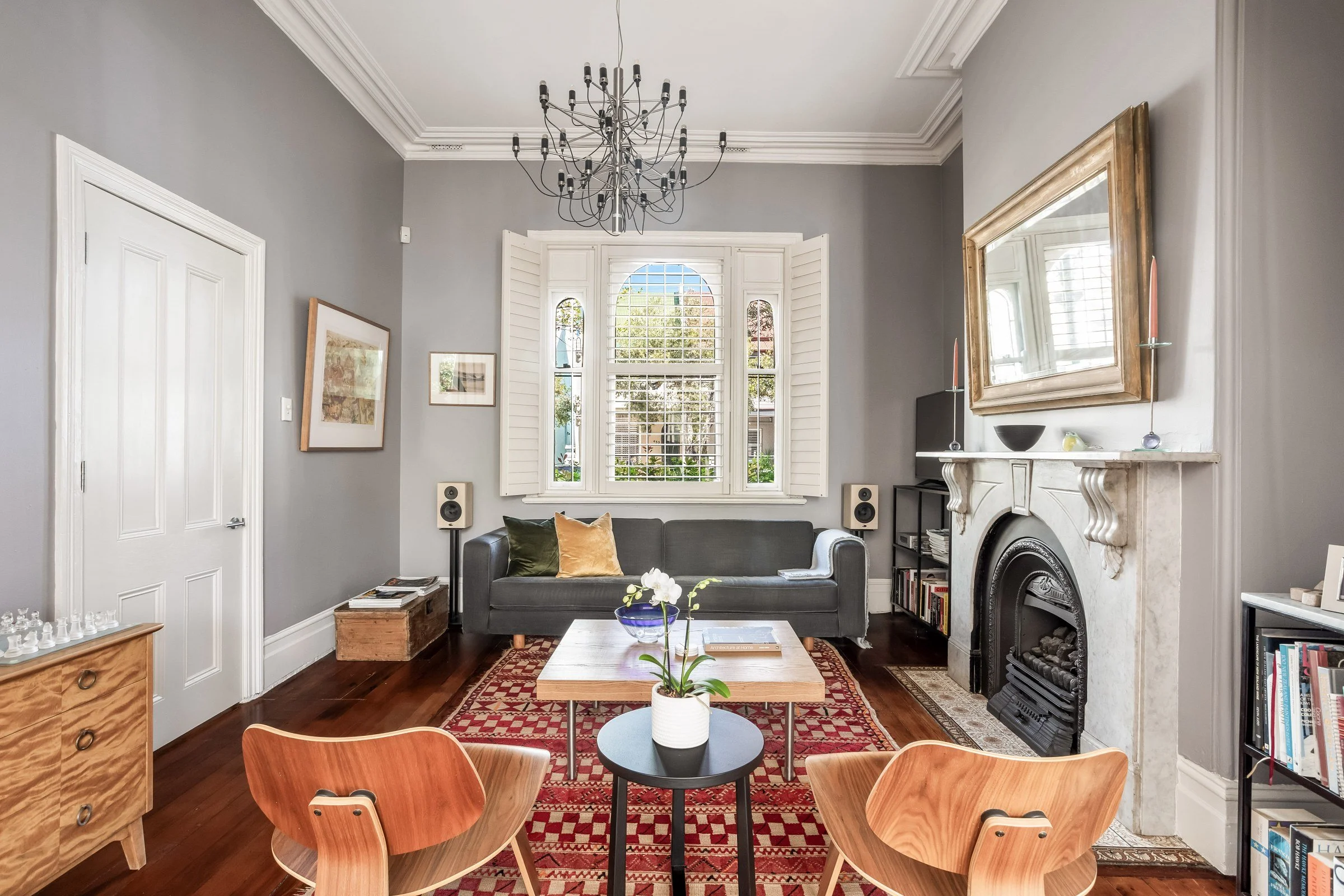 Living room in a Surry Hills terrace with an arched shuttered window, grey walls, a marble fireplace and a red rug, by A Studio Architecture