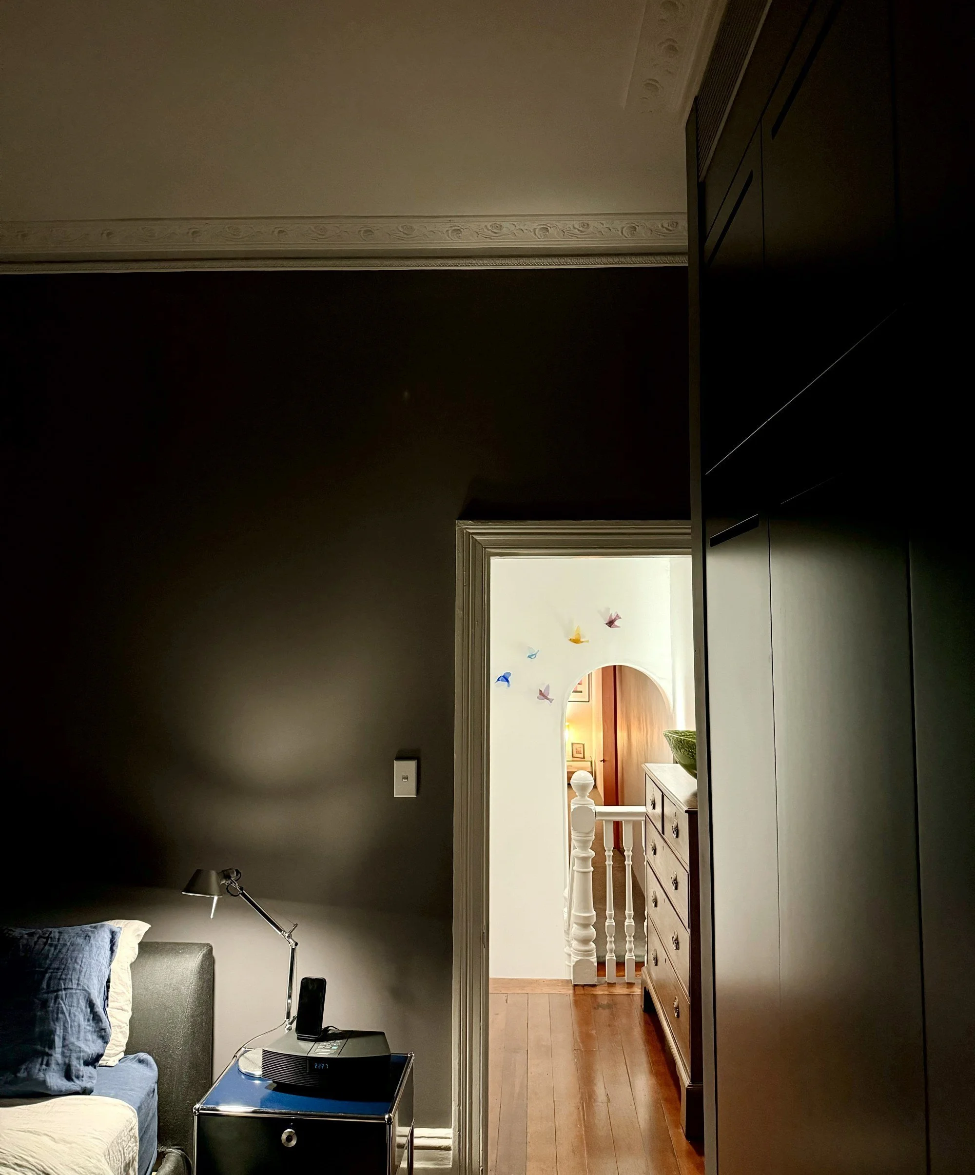 Bedroom in a Surry Hills terrace with dark walls, built-in wardrobe and a view through the doorway to the hallway, by A Studio Architecture