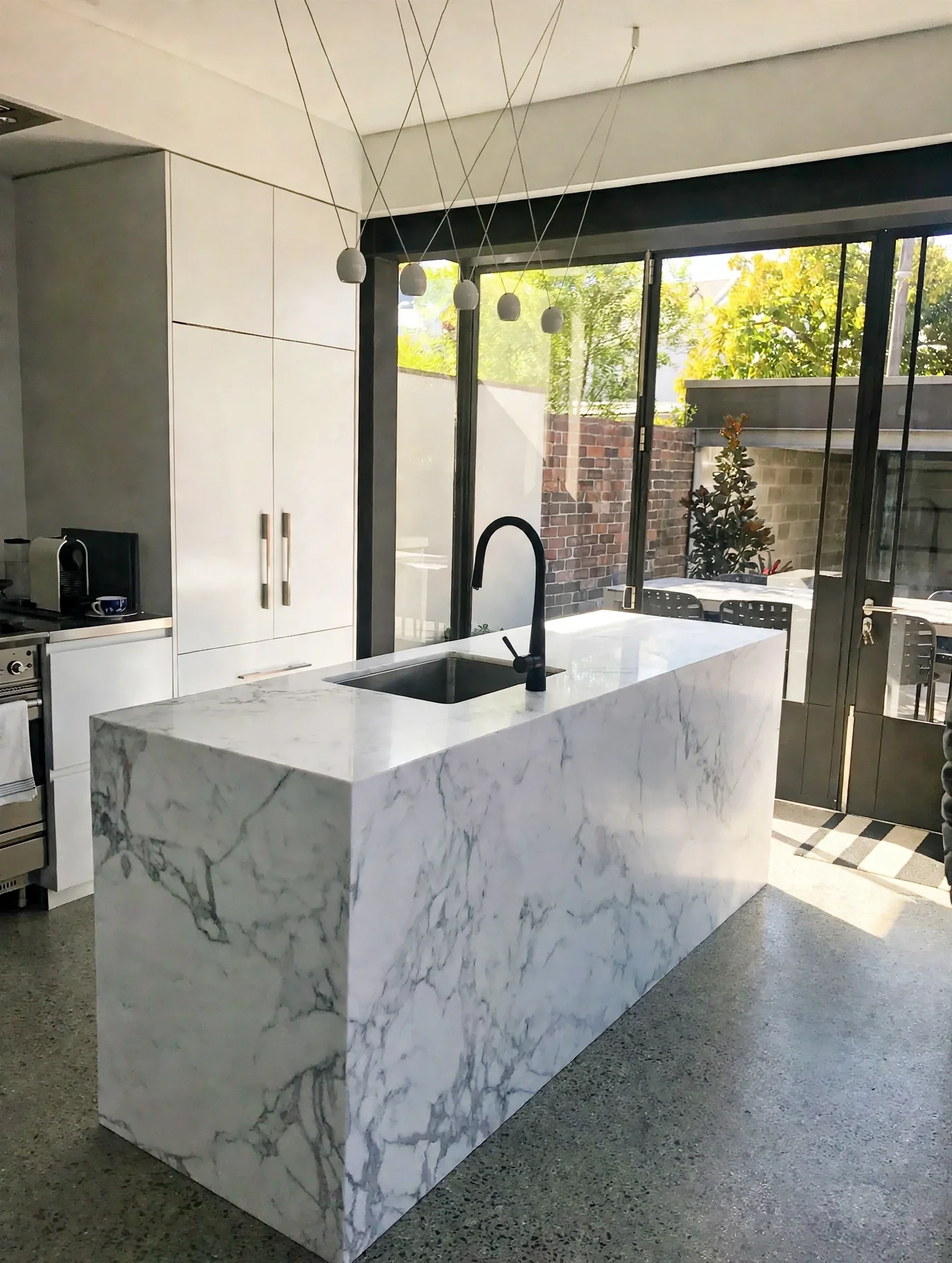 Marble waterfall-edge kitchen island opening to rear courtyard, Erskineville terrace renovation