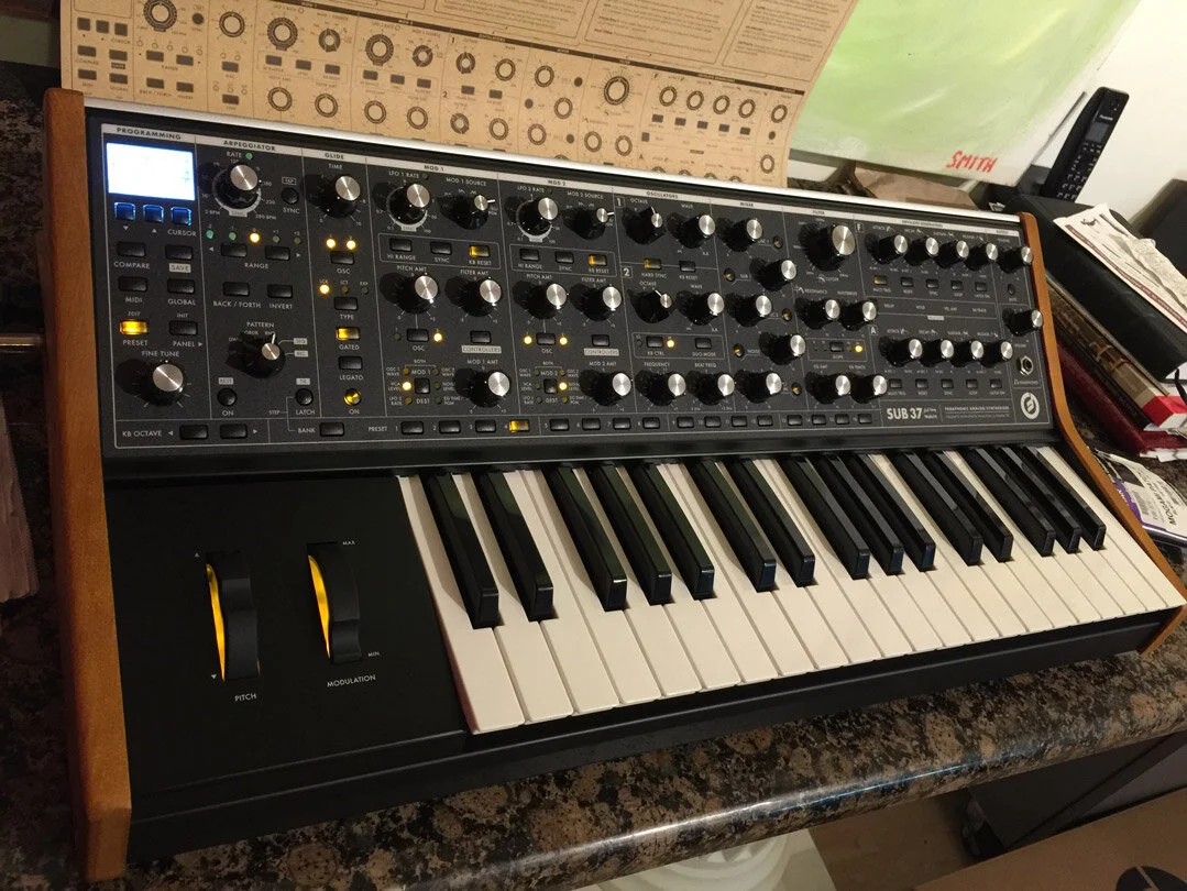 Moog Sub 37 analog synthesizer with knobs, buttons, and keyboard on a countertop. Hashmoder (Omar Hash) (Omar Hashim)