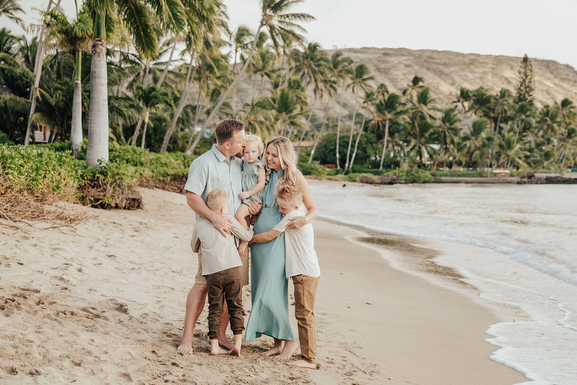Family on a rocky beach at sunset, with two children playing and a couple kissing at Carmel , California.