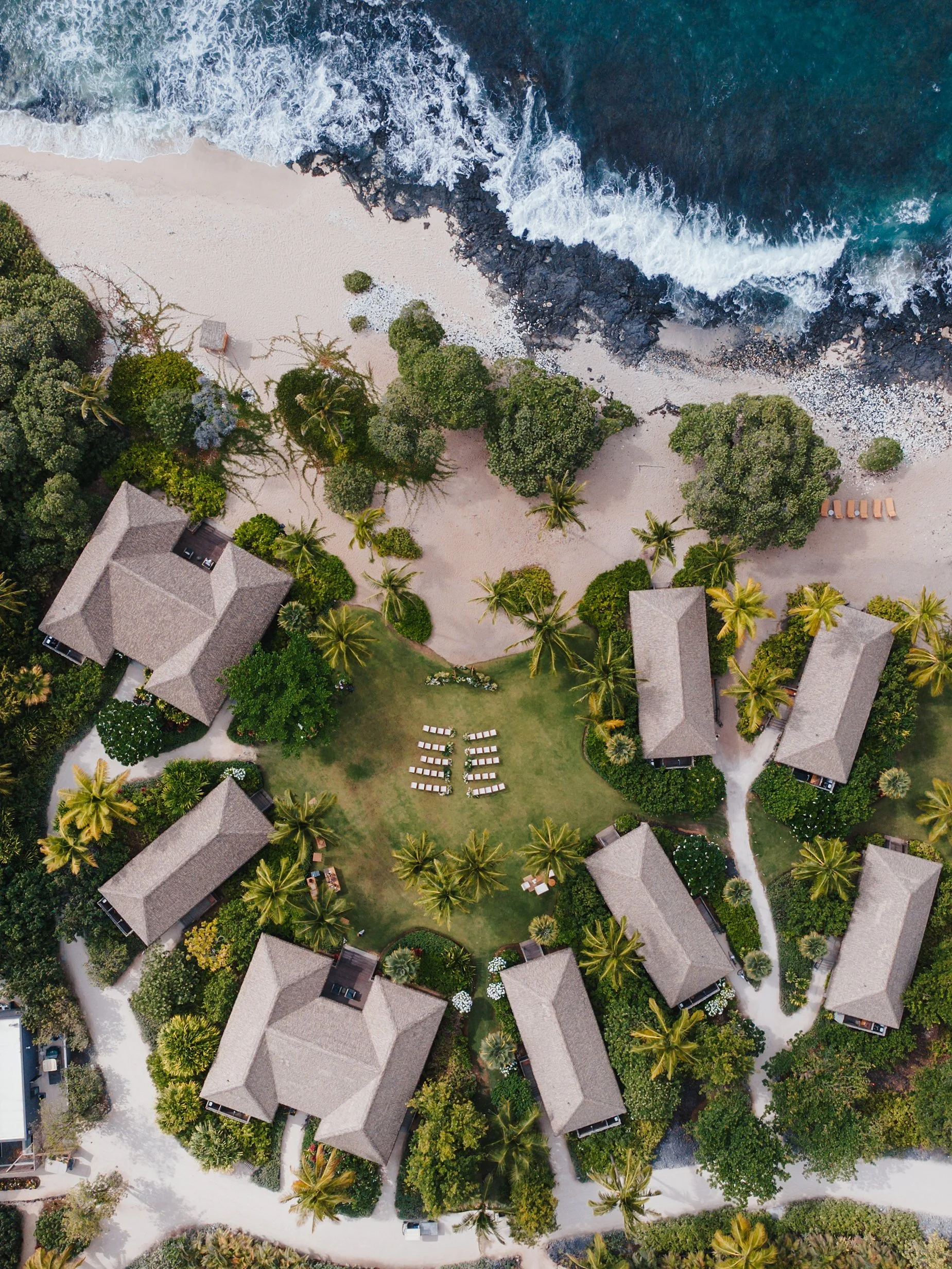     Overhead drone view of oceanfront resort surrounded by palm trees at Kona Village in Hawaii