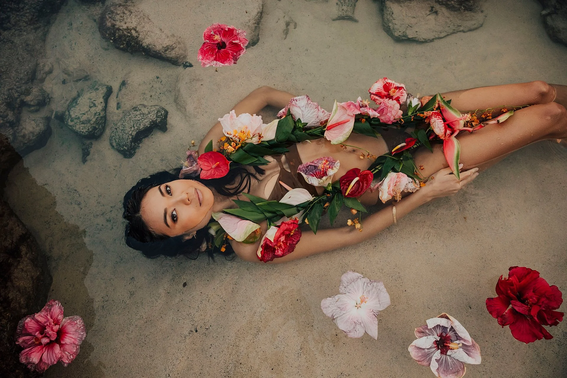     Woman surrounded by tropical flowers during artistic beach portrait session in Hawaii