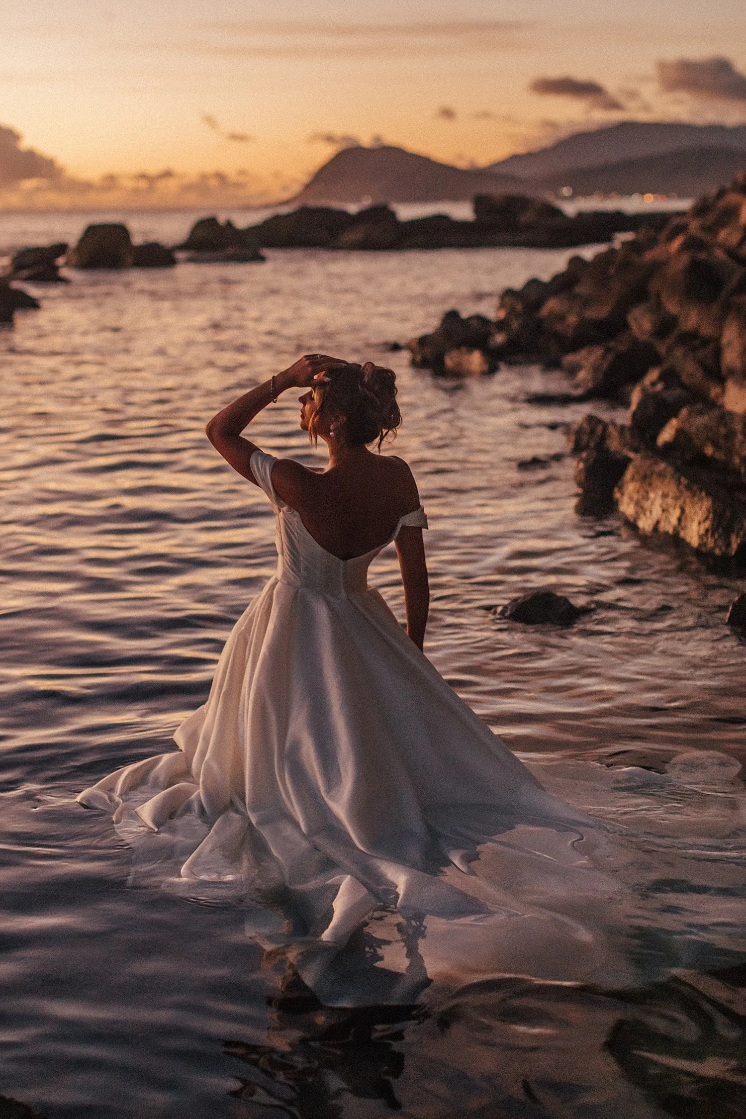     Romantic sunset bridal portrait standing in shallow ocean water in Hawaii