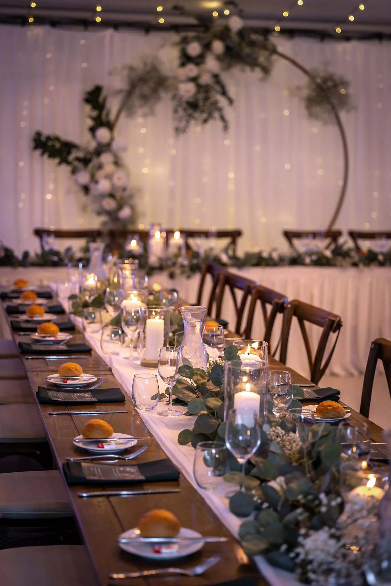 Reception table styled with soft fairy lighting and candles, creating a romantic evening wedding atmosphere.