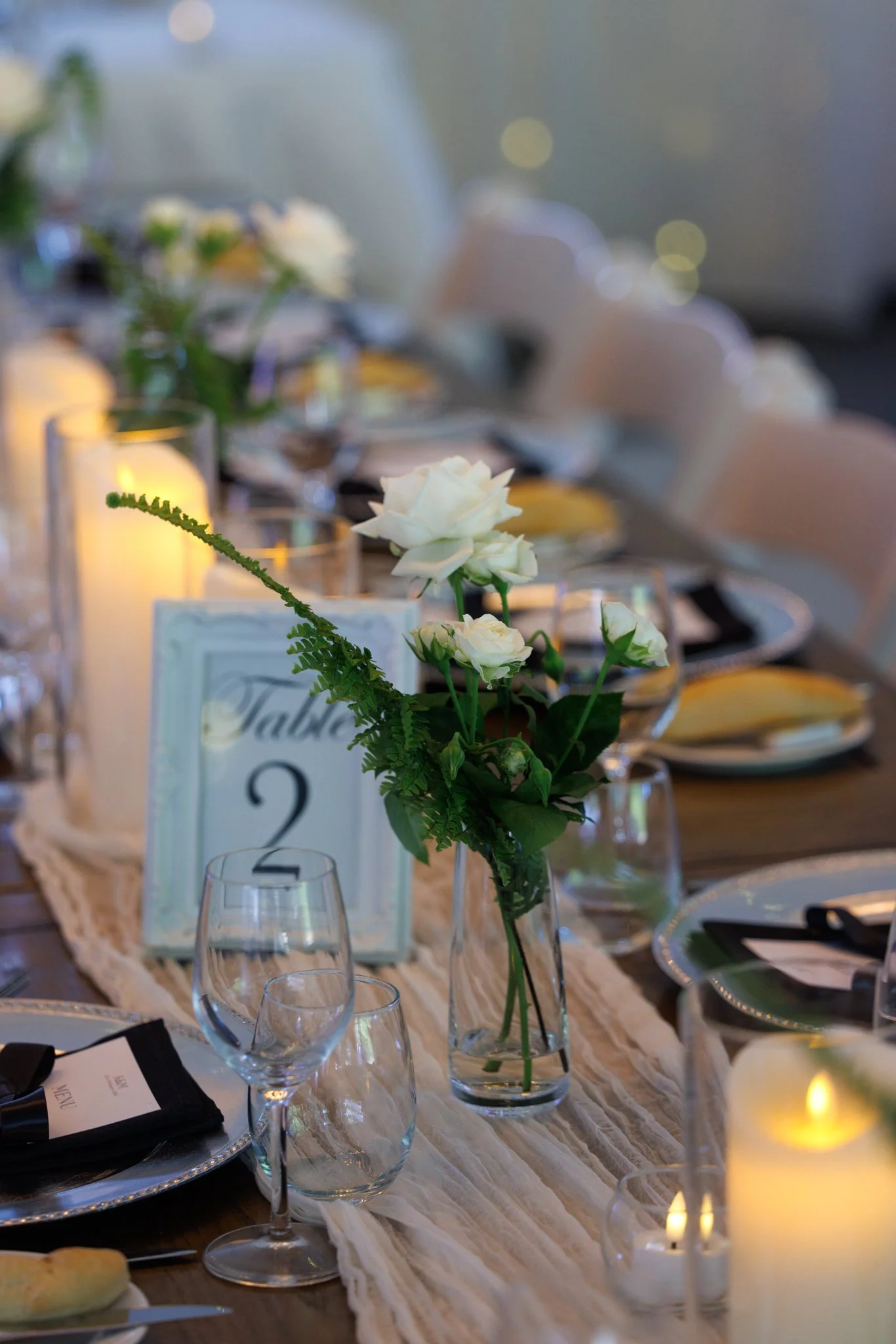 Wedding table number styling with florals and glassware, adding detail to reception décor.