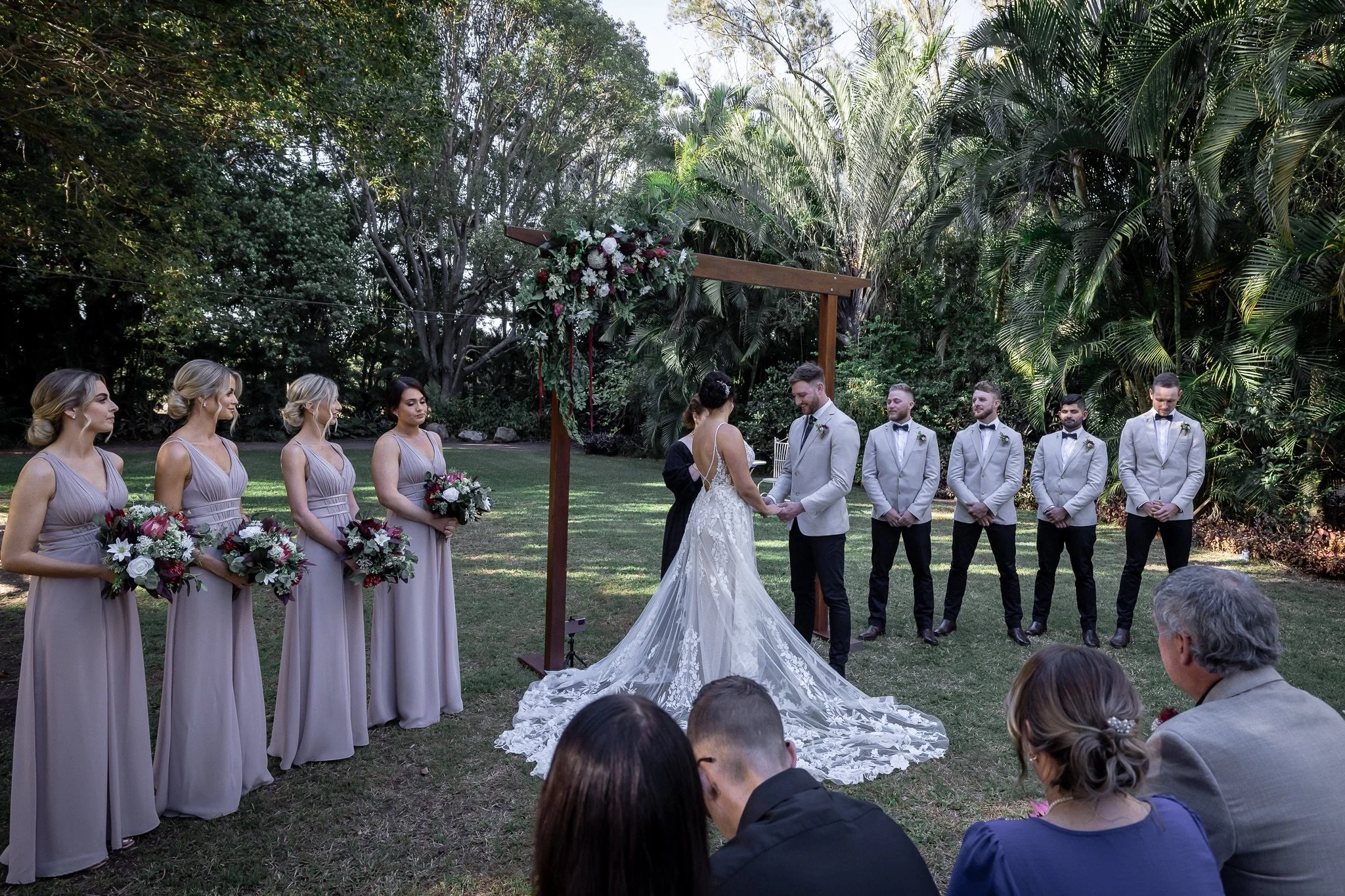 Wedding ceremony with bridal party gathered in a garden setting, creating a relaxed and intimate Queensland wedding atmosphere.