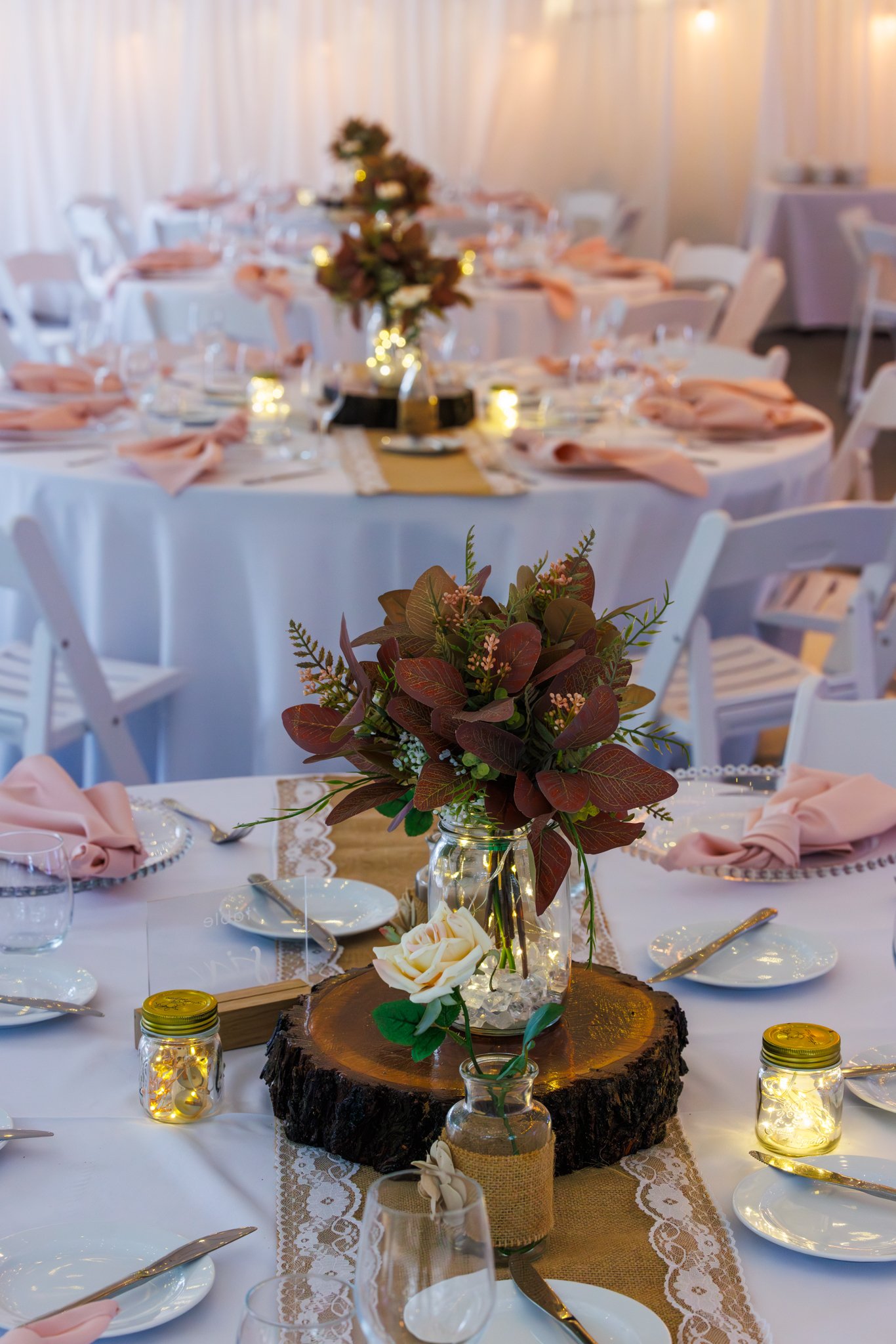Styled wedding reception tables with floral centrepieces inside a marquee at a Queensland garden venue