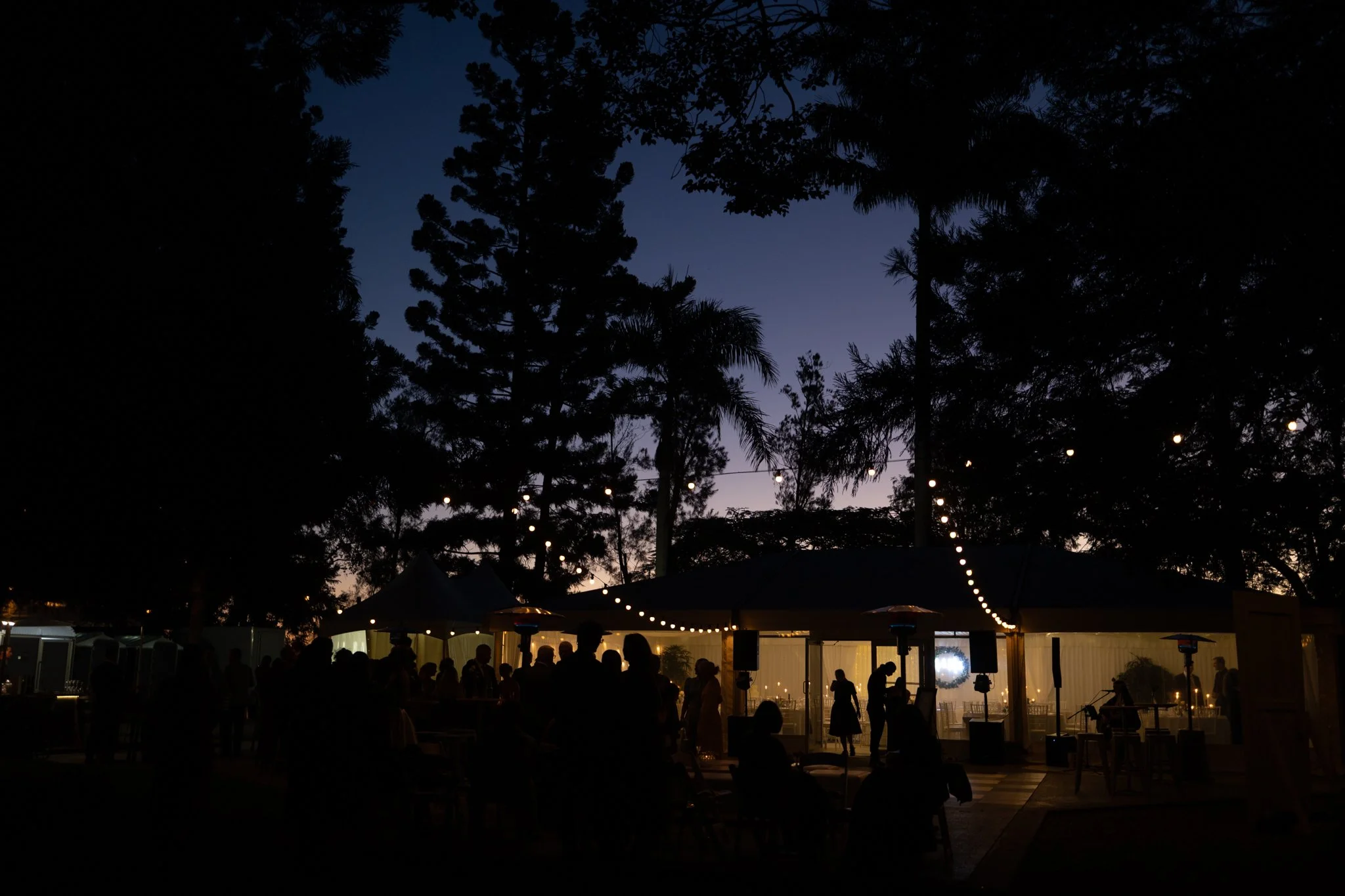 As daylight fades, the gardens come alive with festoon lights, warm conversation and the relaxed atmosphere of an unforgettable wedding celebration.