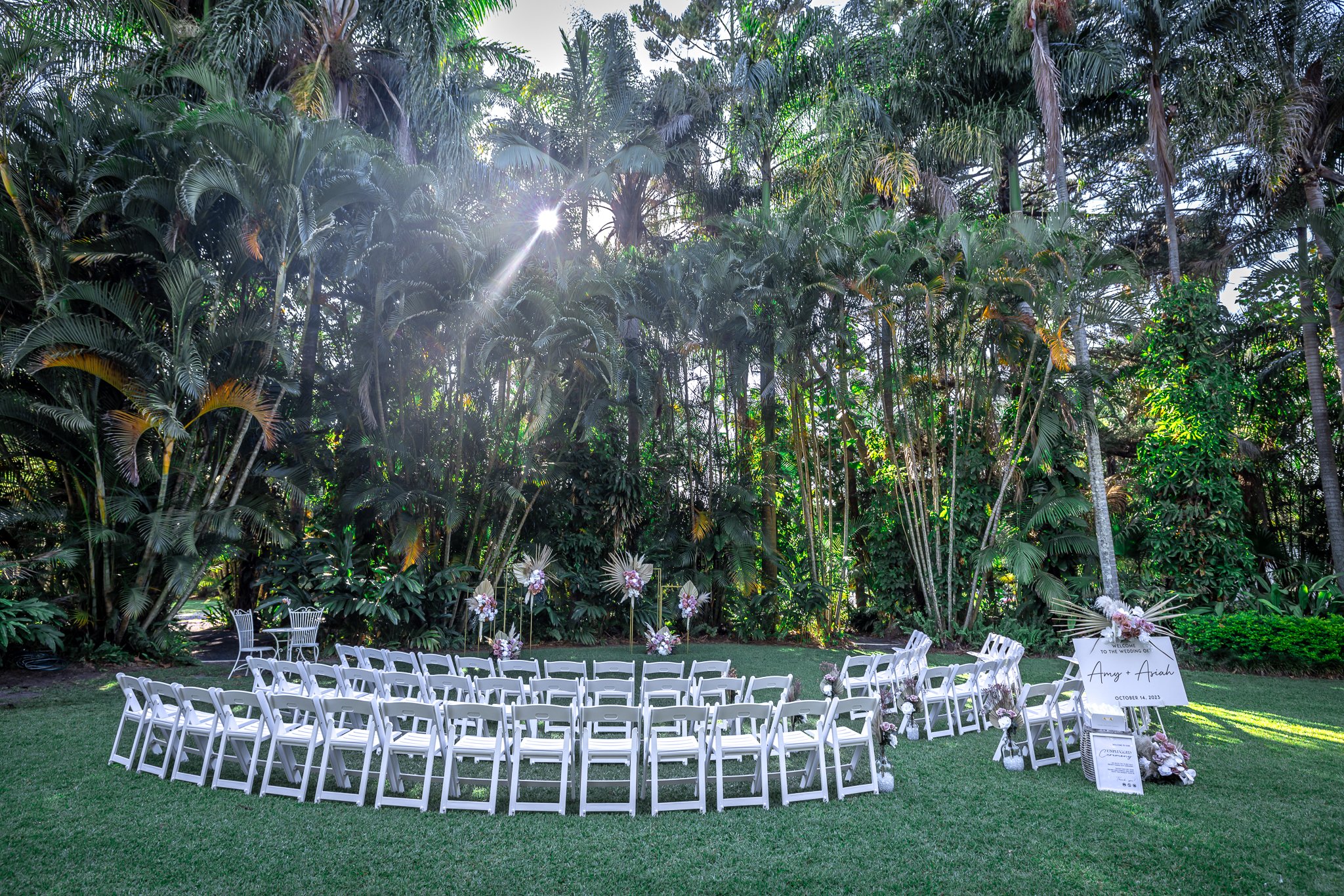 Elegant outdoor wedding ceremony with white guest seating set among tropical gardens in a Queensland venue.