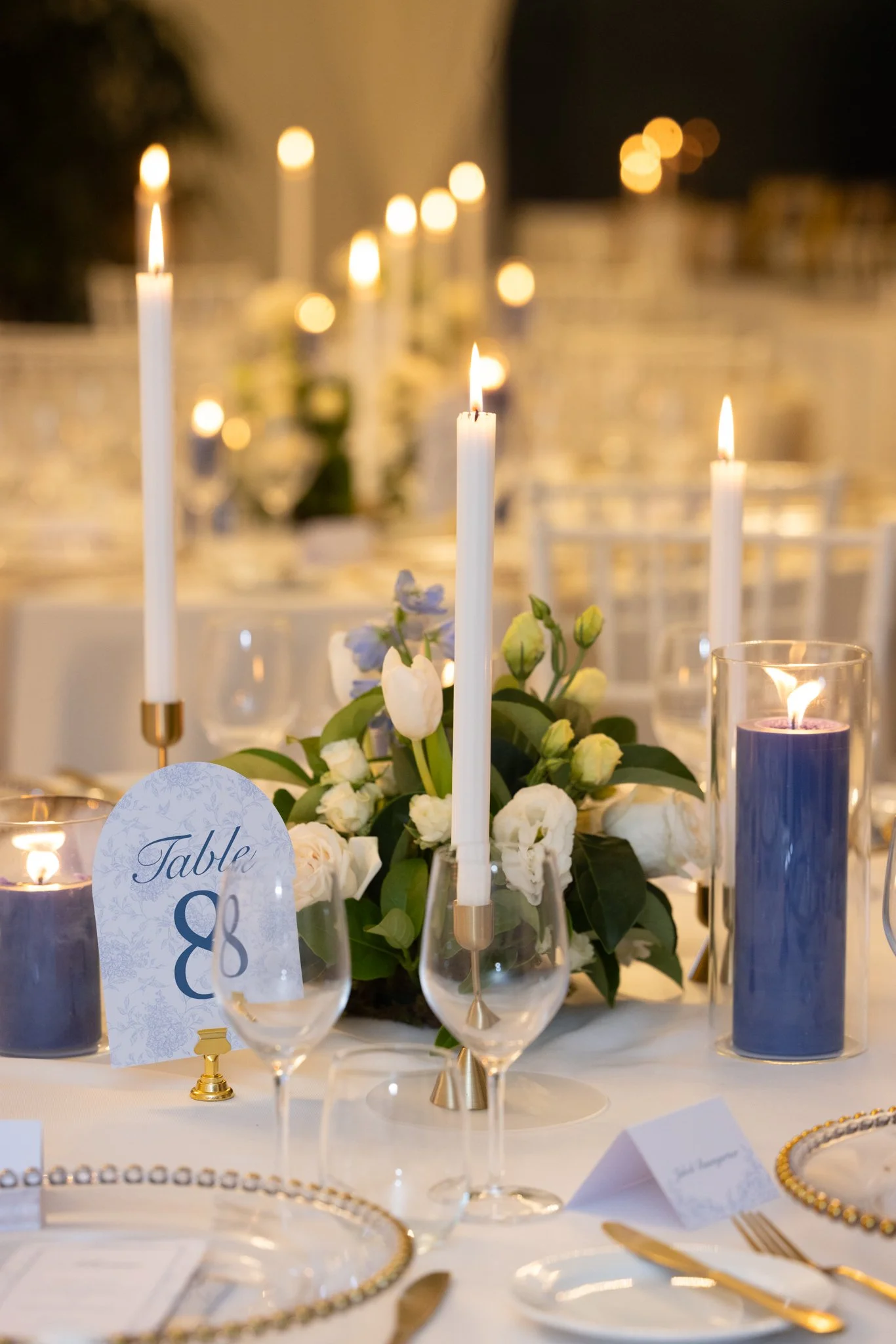 Romantic candlelit reception styling featuring blue pillar candles, white florals and elegant table settings, creating an intimate and sophisticated wedding atmosphere at In The Grove.