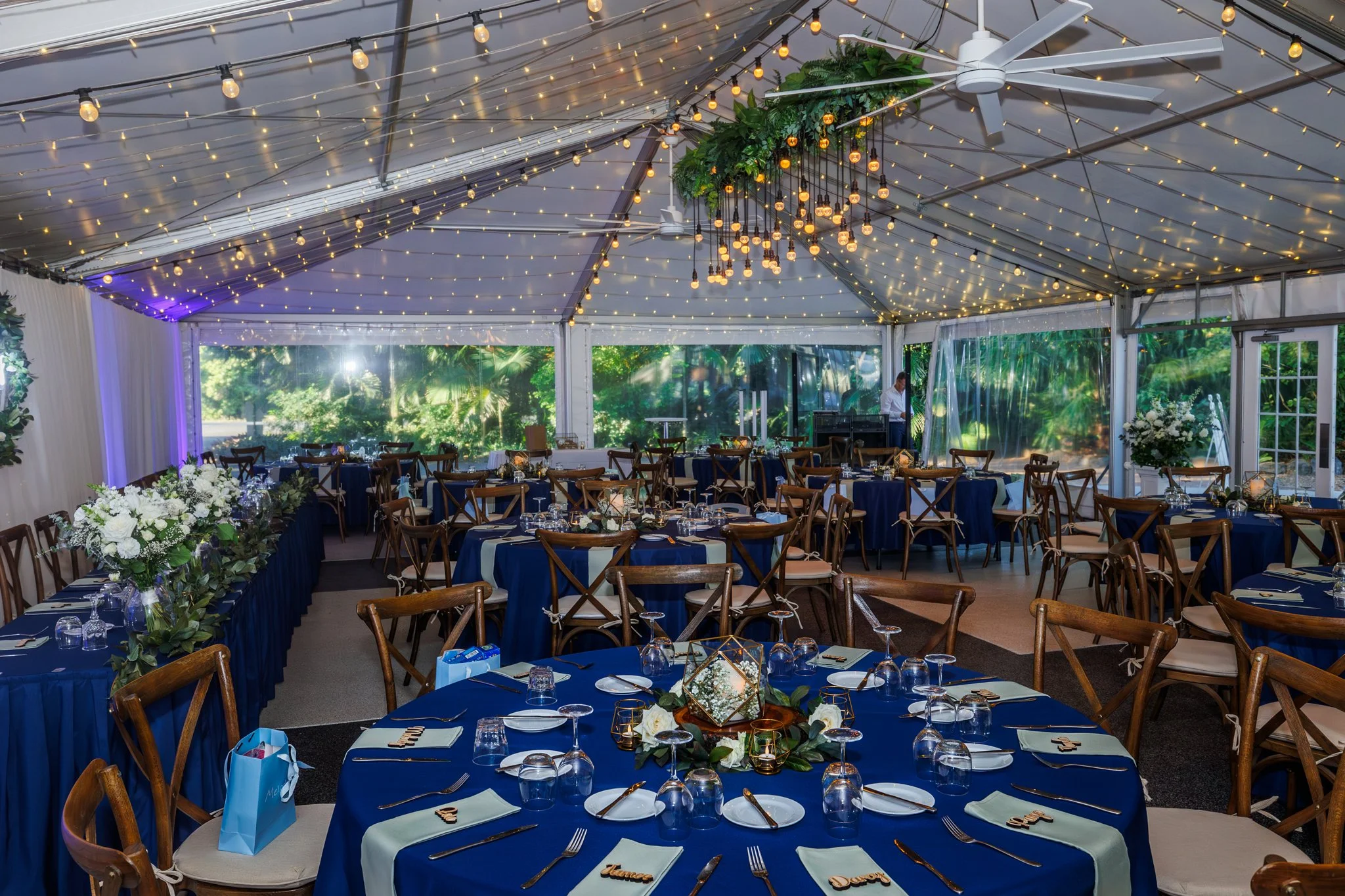 Wedding reception styled with navy and gold tones, showcasing personalised table décor and elegant place settings.
