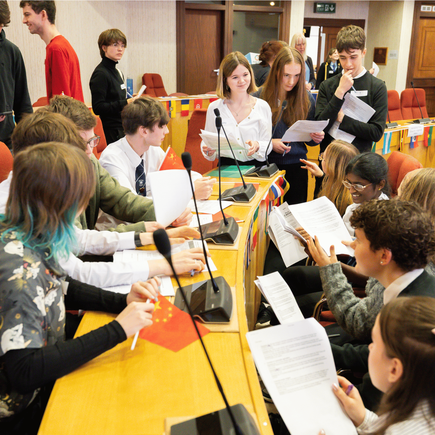A group of teenage school pupils gathered around a table negotiating during a Mock COP
