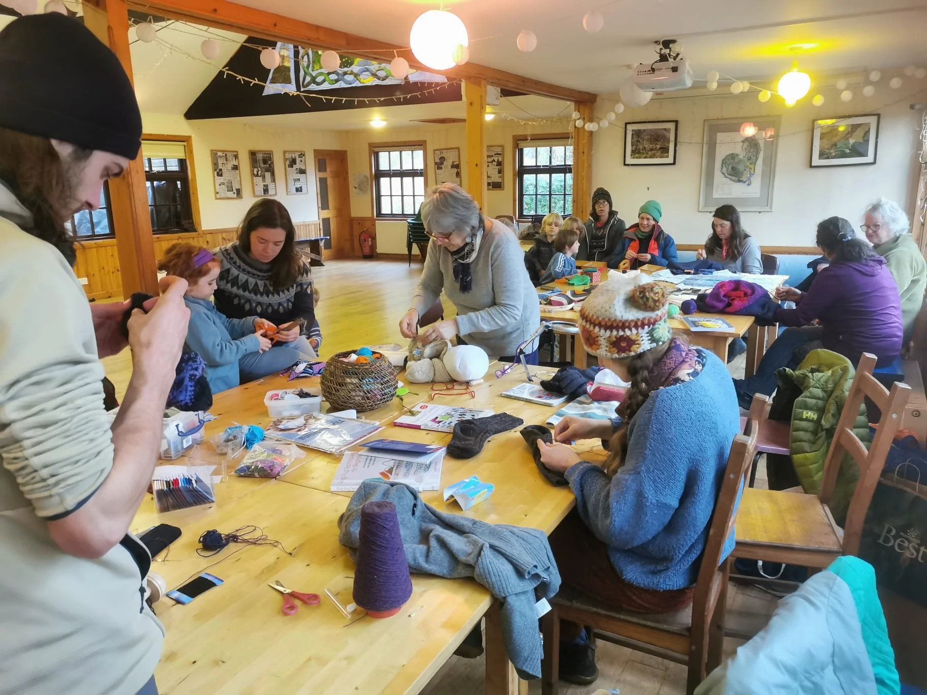 A group of people of various ages taking part in a mending session with yarn
