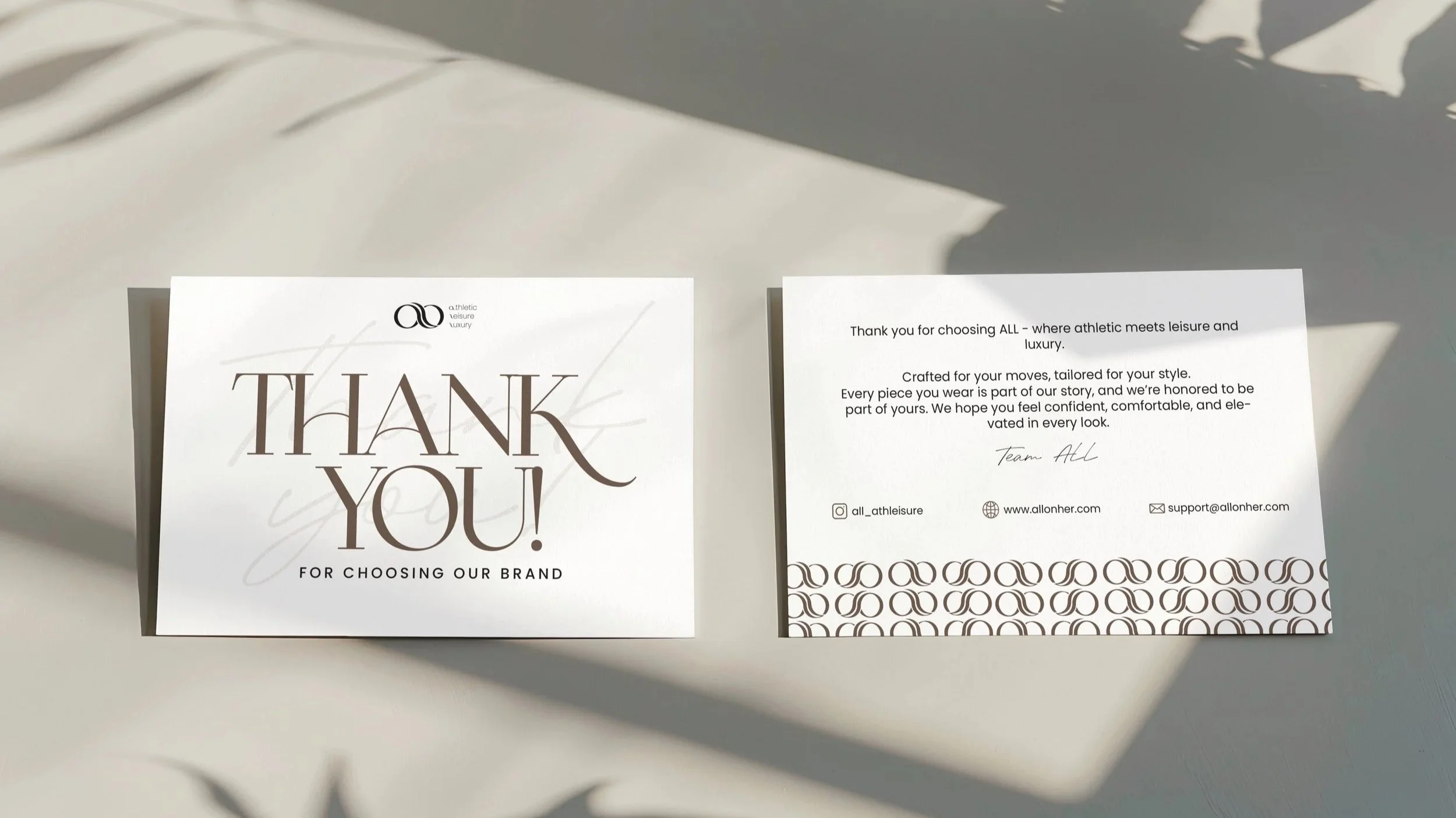 A thank you card and a note card placed on a white surface, with shadows cast across the cards.
