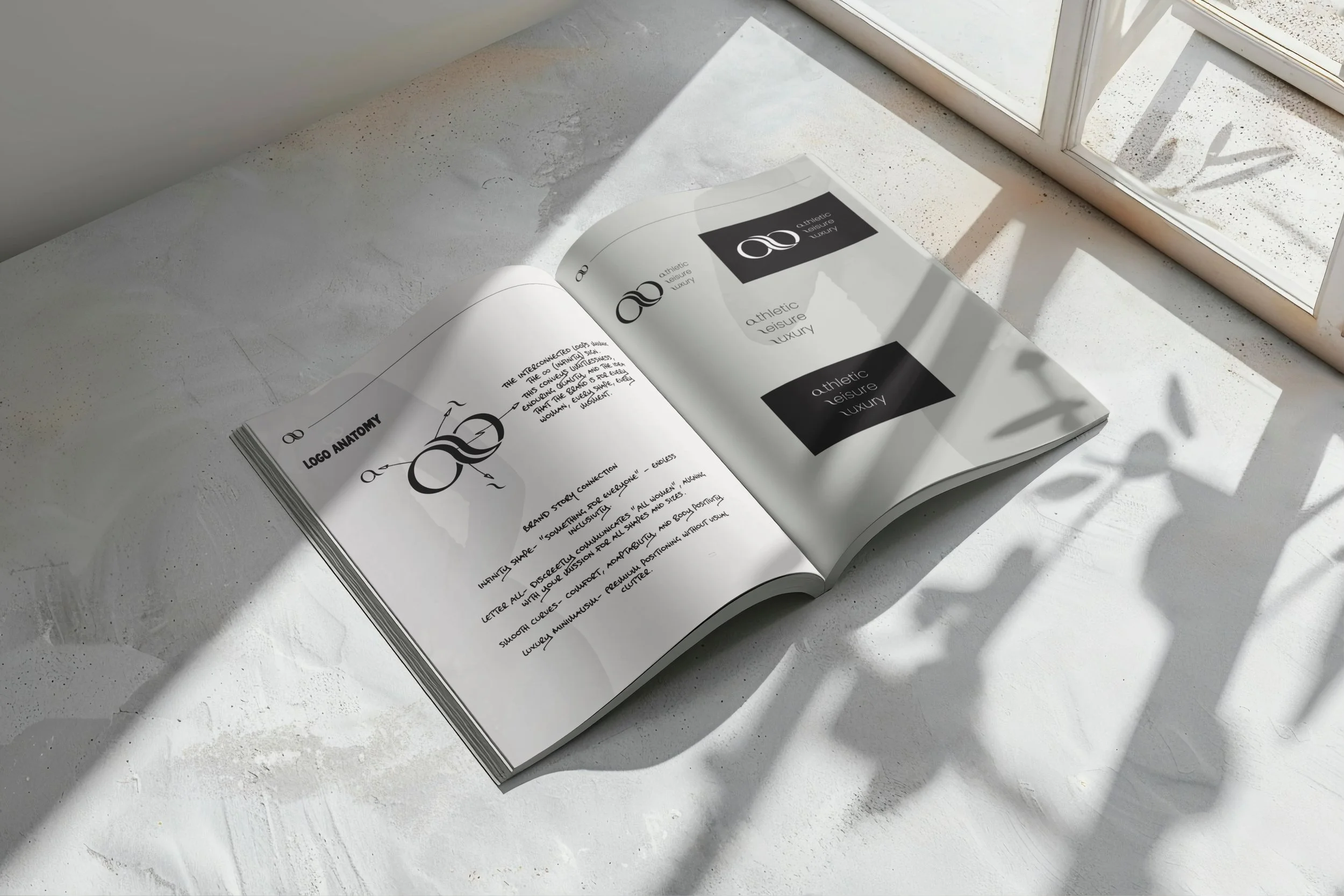Open magazine on a white surface near a window with sunlight casting shadows, showing logo design and branding concepts for 'athletic leisure luxury'.