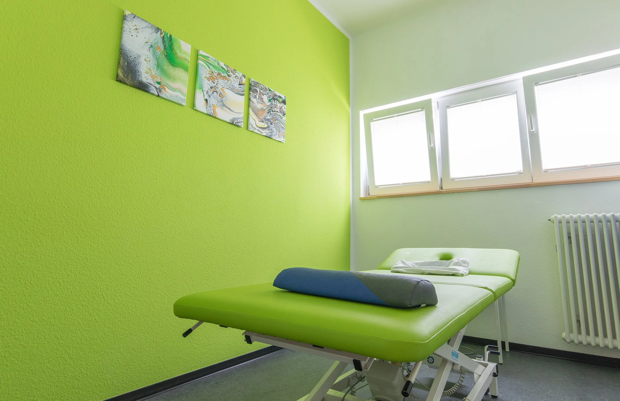 Behandlungszimmer mit grüner Wand, Krankenzimmer mit Behandlungsstuhl, Fenster und Wandbild
