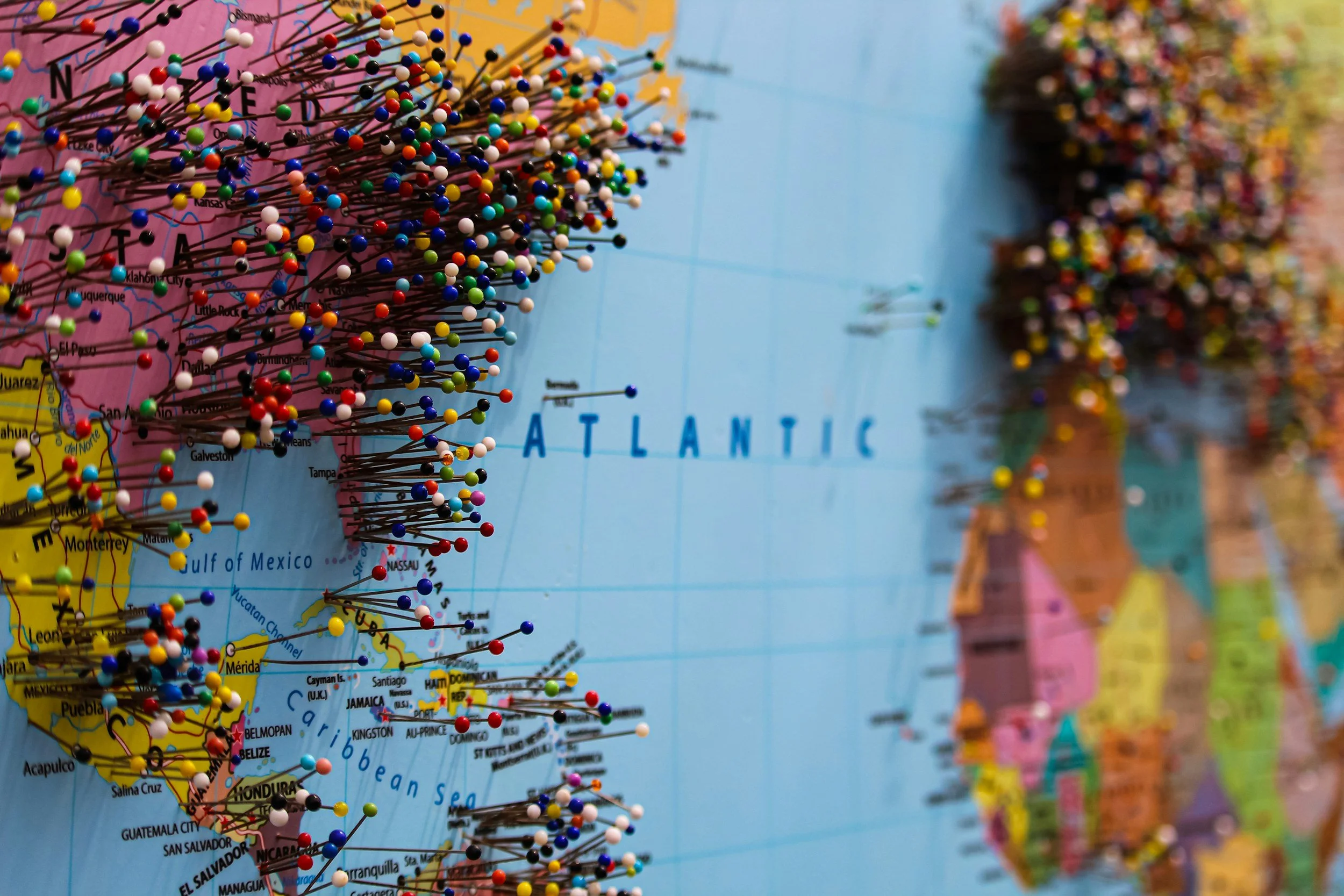A world map with numerous colorful pushpins marking various locations, focusing on the southeastern United States and the Atlantic Ocean.