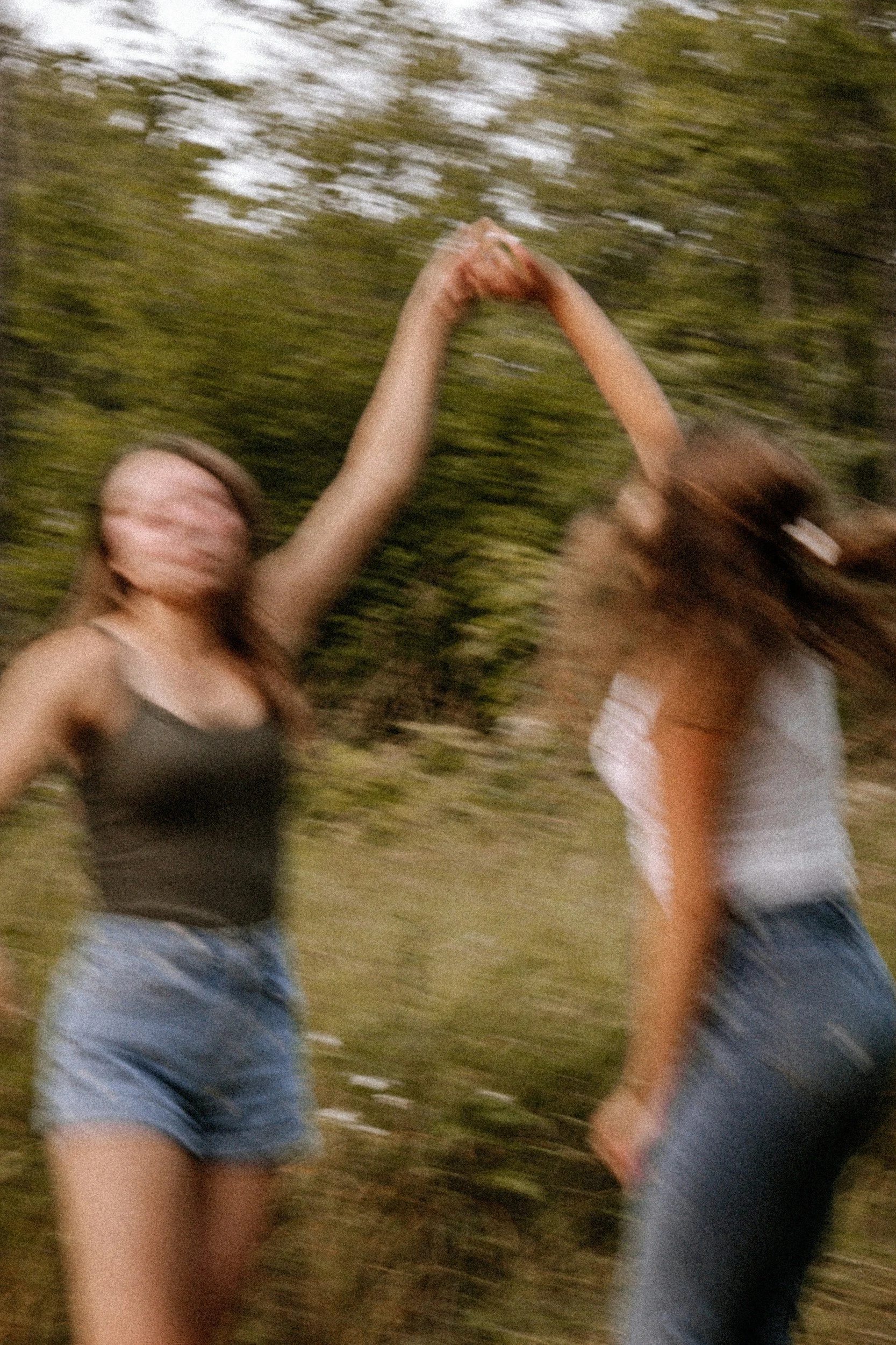 Two people, a woman and a man, are outdoors holding hands with blurred background of trees, indicating movement or motion.
