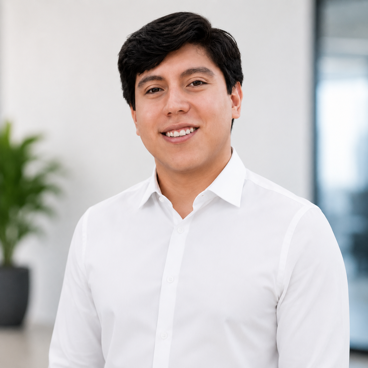 Joven hombre sonriendo con camisa blanca en oficina moderna.