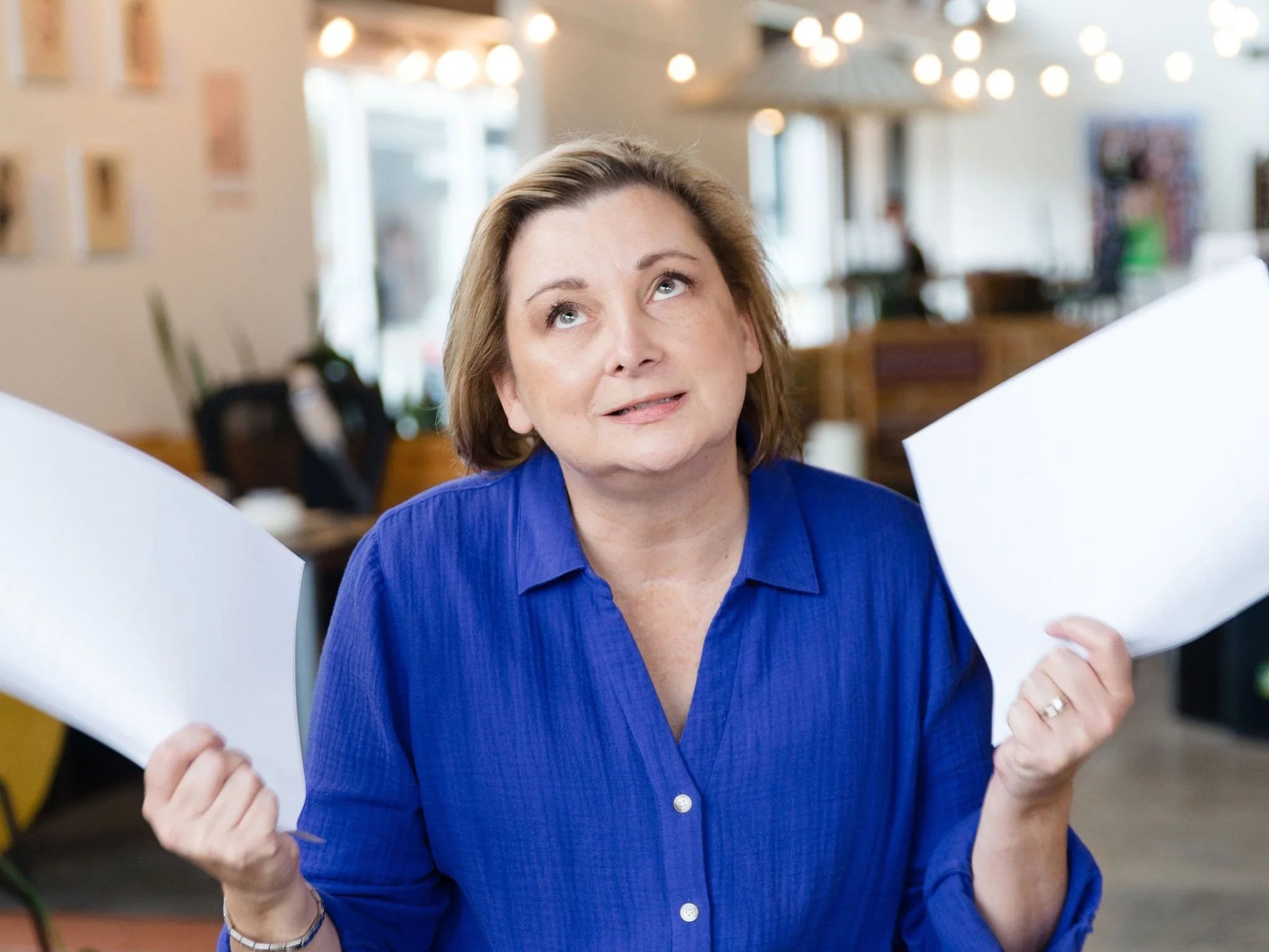 Jodie holding two sheets of paper trying to decide.