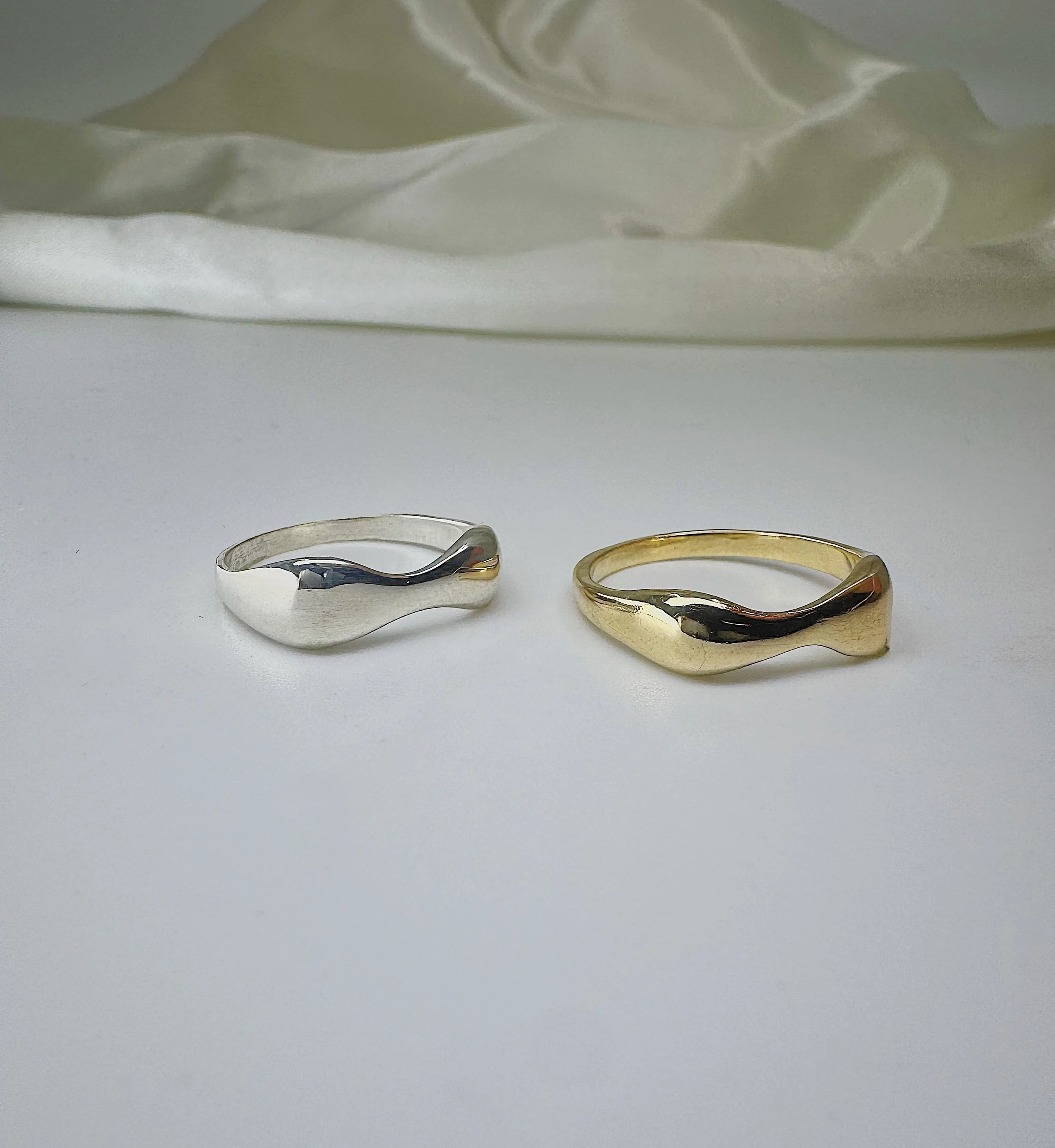 Two rings, one silver and one gold, placed on a white surface with a white background.