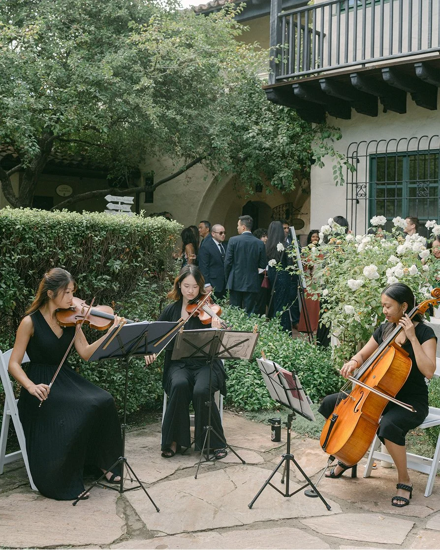 Wedding musicians performing live string music as guests gather at a San Francisco event venue