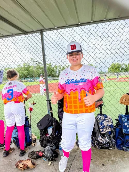 Kid flashes the thumbs up in an ice cream drip baseball uniform.