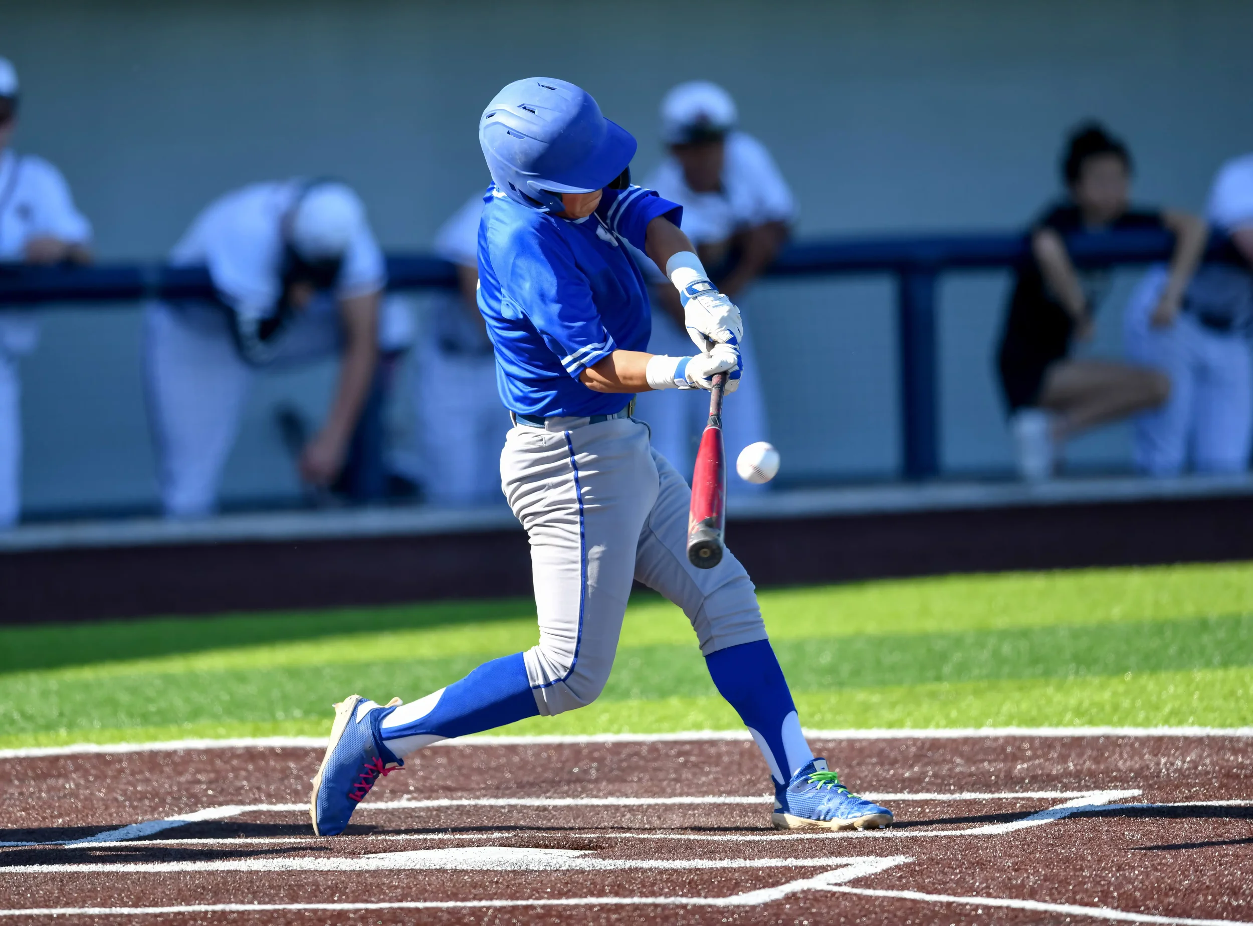 Baseball player in striped pants and stirrups hitting a ball.