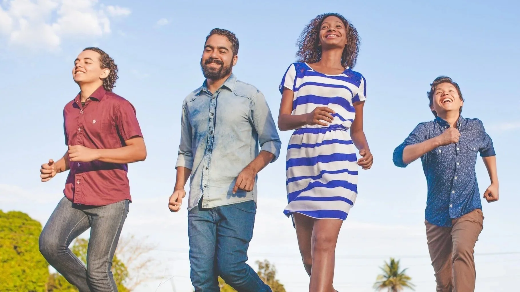 Family members running and smiling with clear blue skies in the background