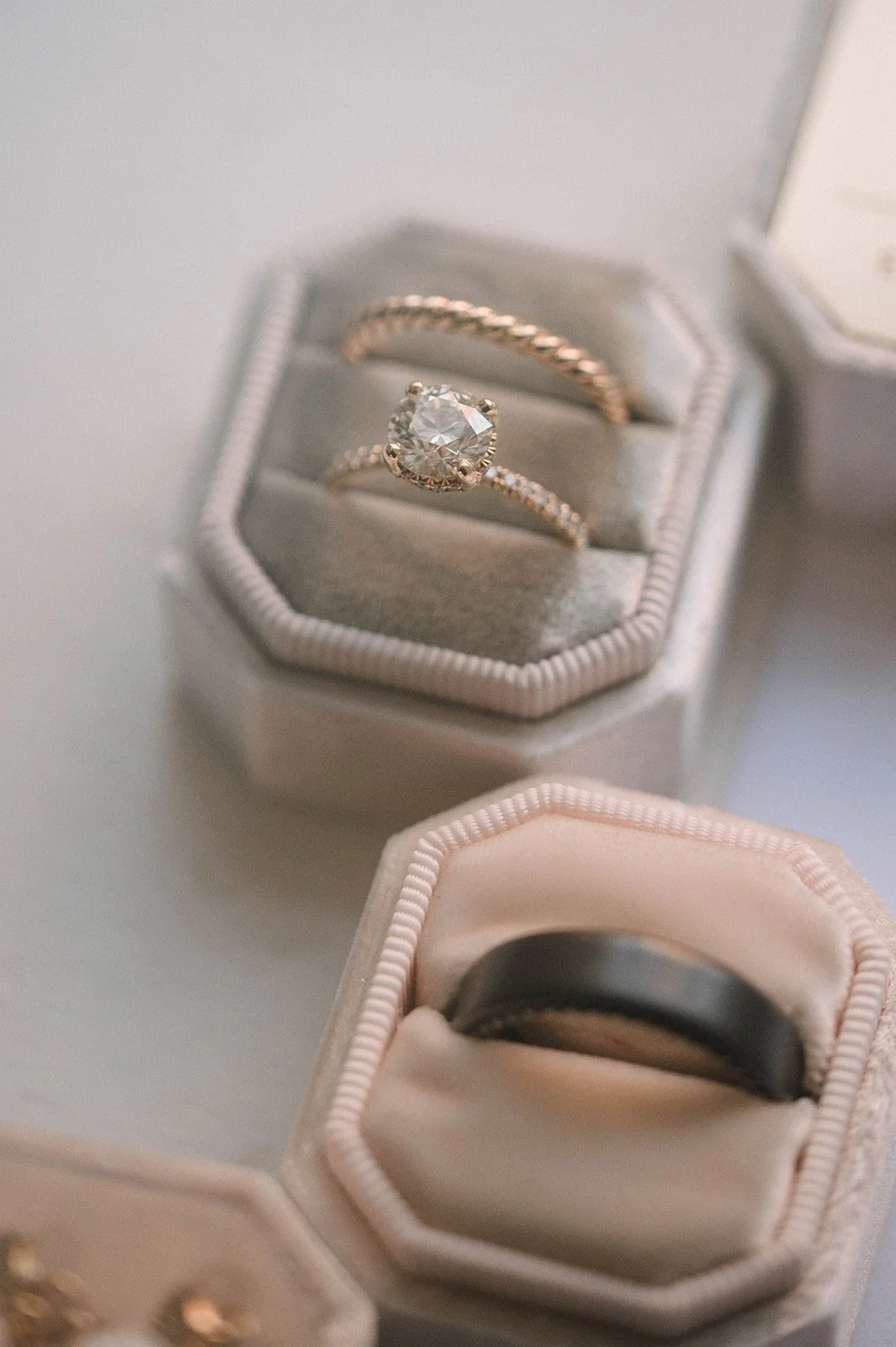 Close-up of a jewelry box with a diamond engagement ring and wedding band inside, and another ring in a different box nearby.
