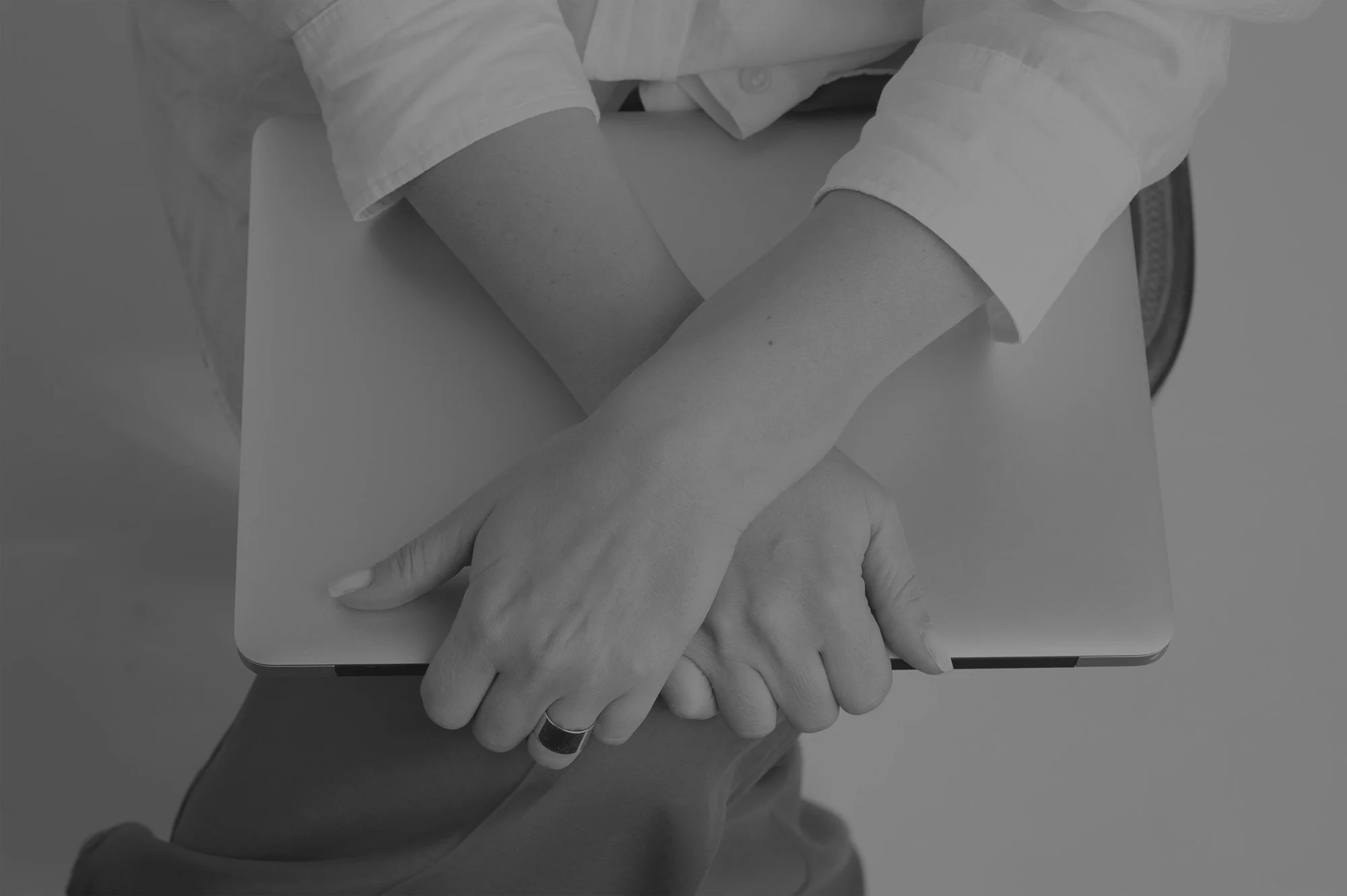 Two people shaking hands with one person using a laptop on a table.