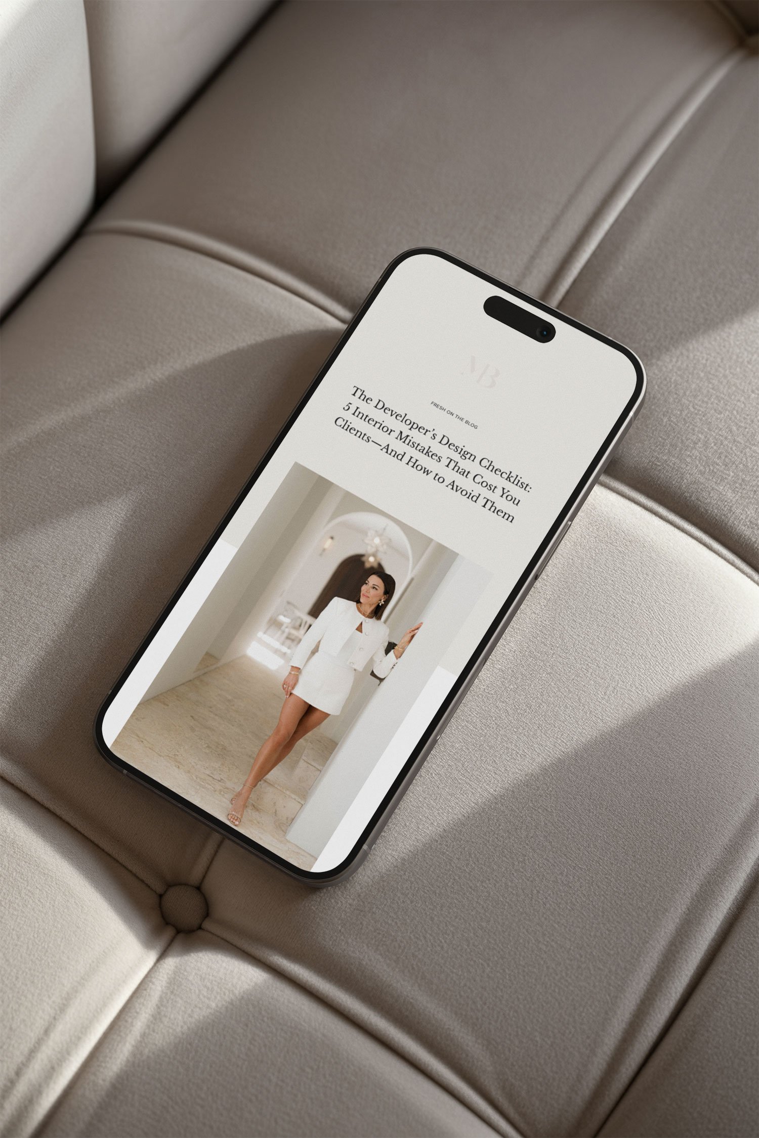 A smartphone displaying an article titled 'The Developer's Design Checklist: 5 Interior Mistakes That Cost You Clients—And How to Avoid Them' with an image of a woman in a white dress standing in a luxurious interior hallway.