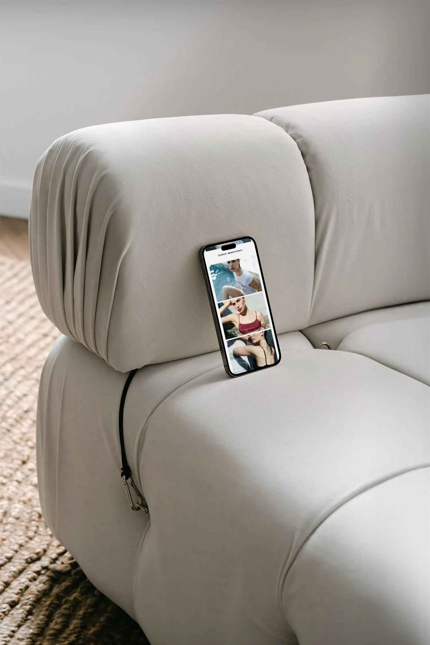 Smartphone leaning against a white sofa showing photos of women in swimsuits.