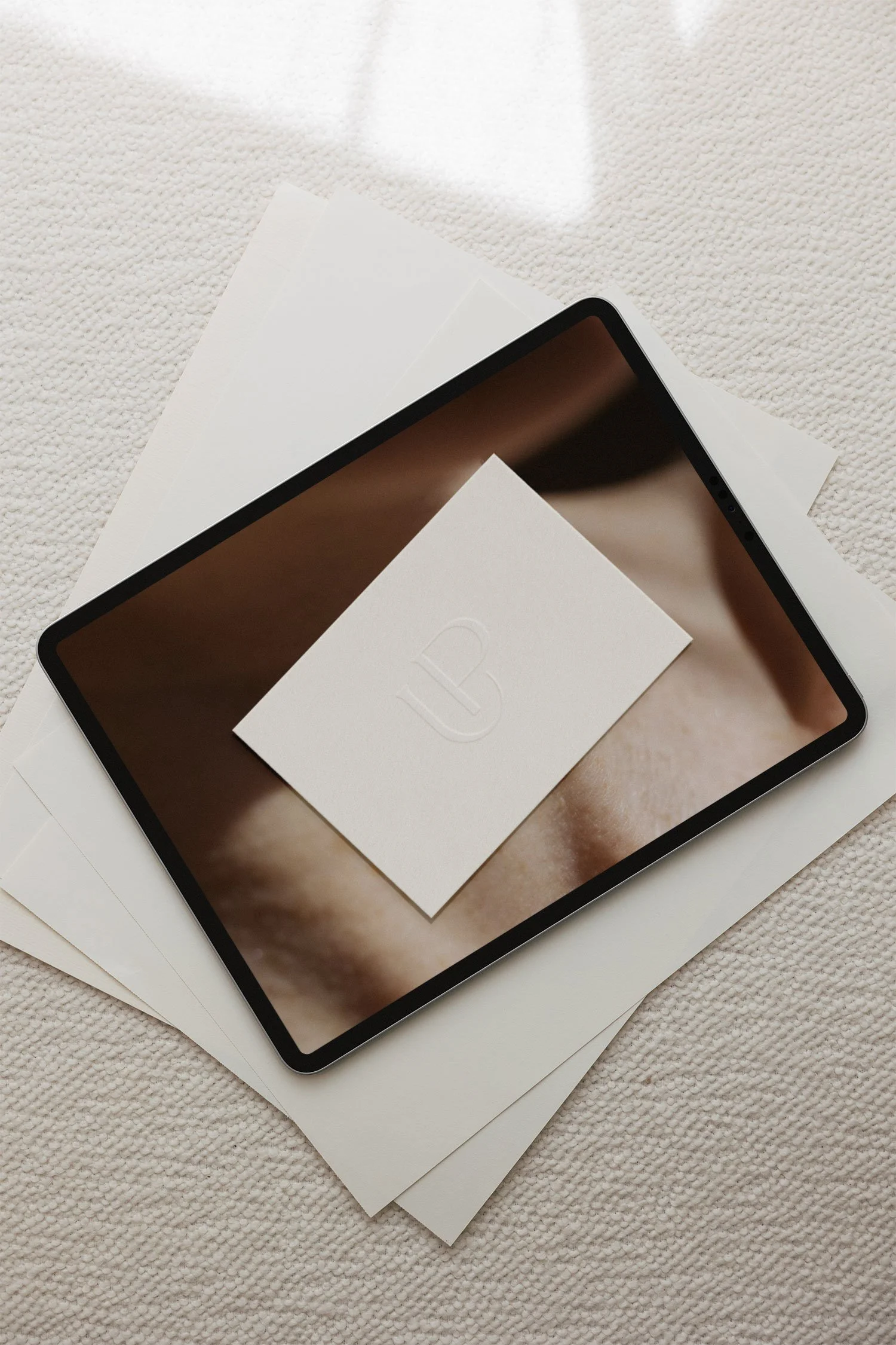 A tablet with a bemer logo on the screen, placed on top of several sheets of white paper.