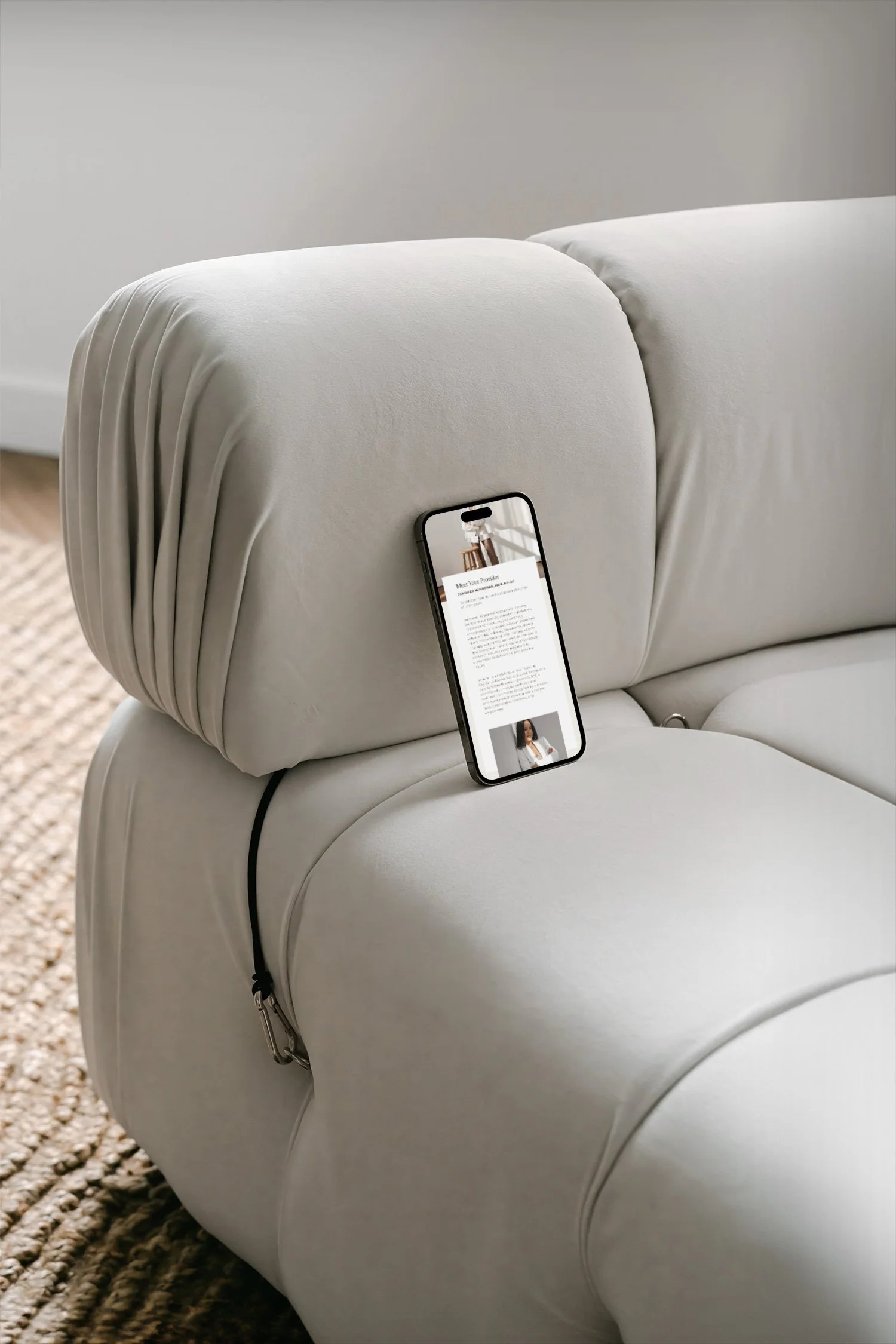 A smartphone placed on the armrest of a light-colored sofa, displaying a webpage or document with text and an image of a woman.