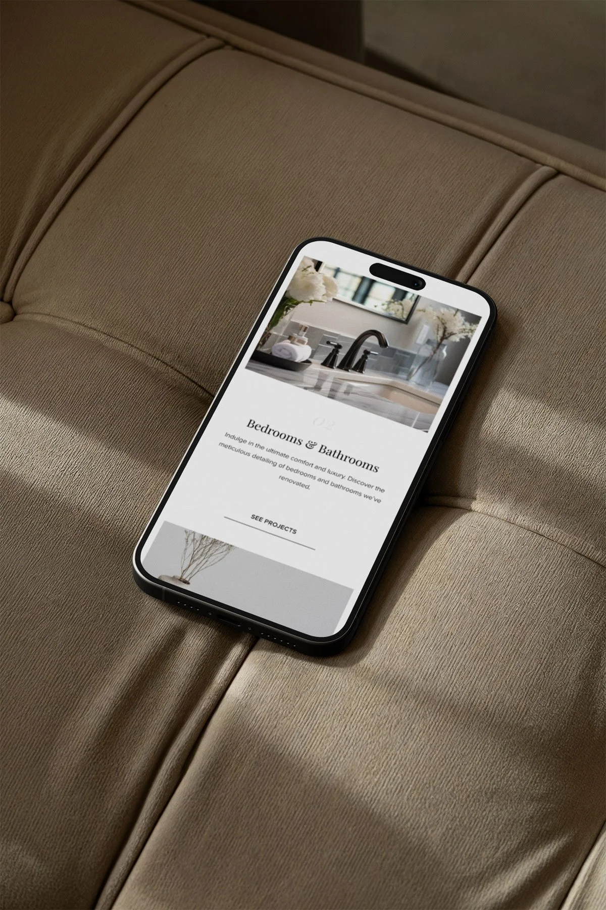 Smartphone displaying a webpage about bedrooms and bathrooms resting on a beige upholstered surface.