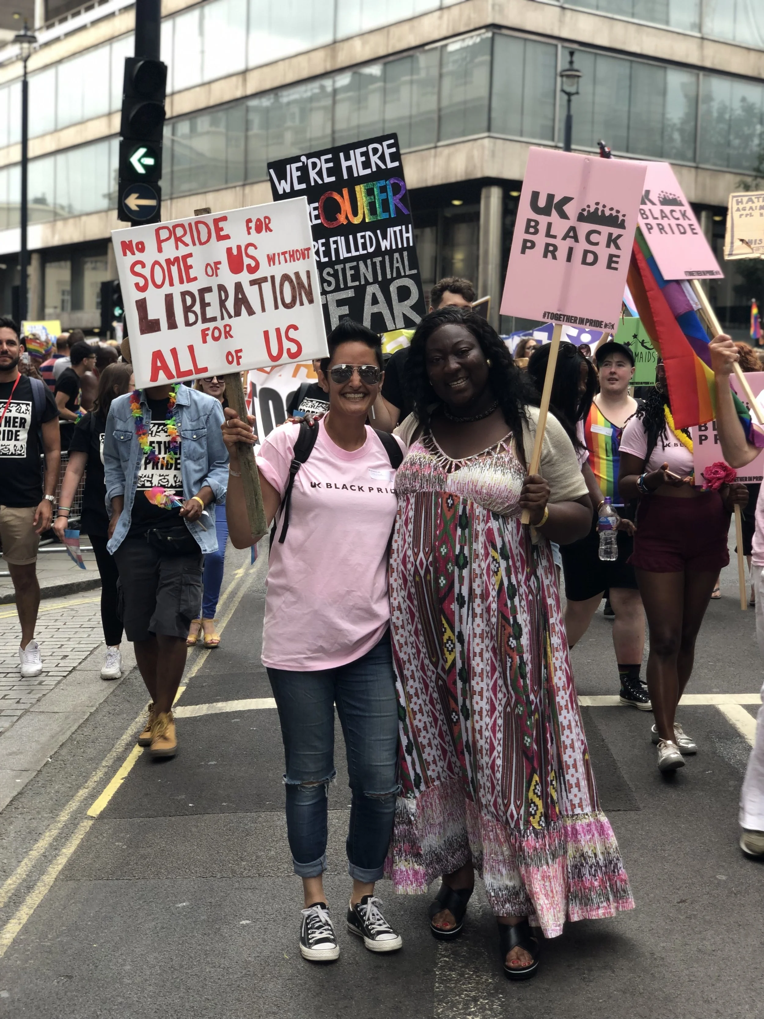 People participating in a Pride march holding various signs and banners advocating for LGBTQ+ rights and equality.