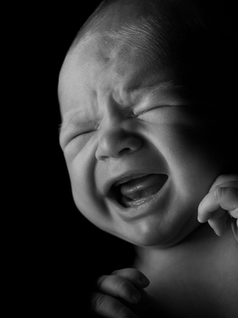 A black and white image of a crying baby.