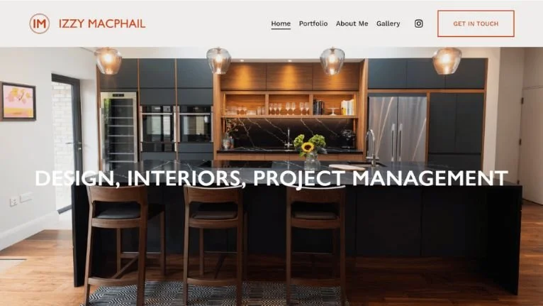 Modern kitchen with black island, bar stools, pendant lights, and wooden accents; web design header for Izzy Macphail Design.