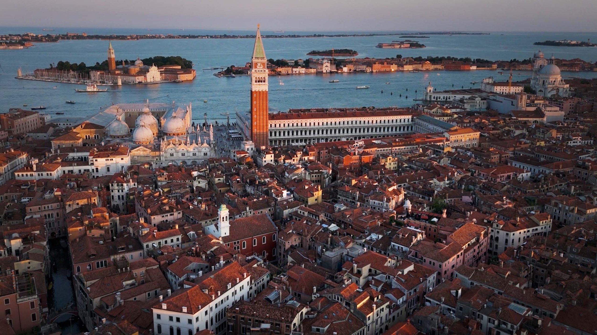 Aerial drone view of Piazza San Marco in Venice, showing St Mark’s Square, the historic architecture and surrounding rooftops in the heart of the city.
